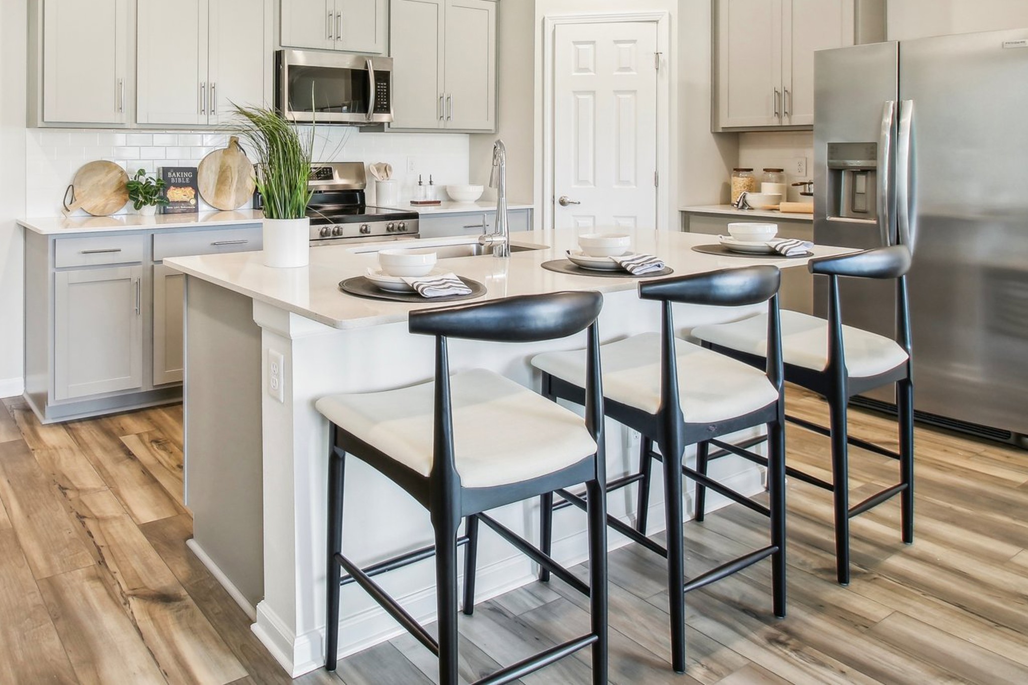 Modern kitchen with sleek gray cabinetry, stainless appliances, island with bar stools in Surprise City Center home.