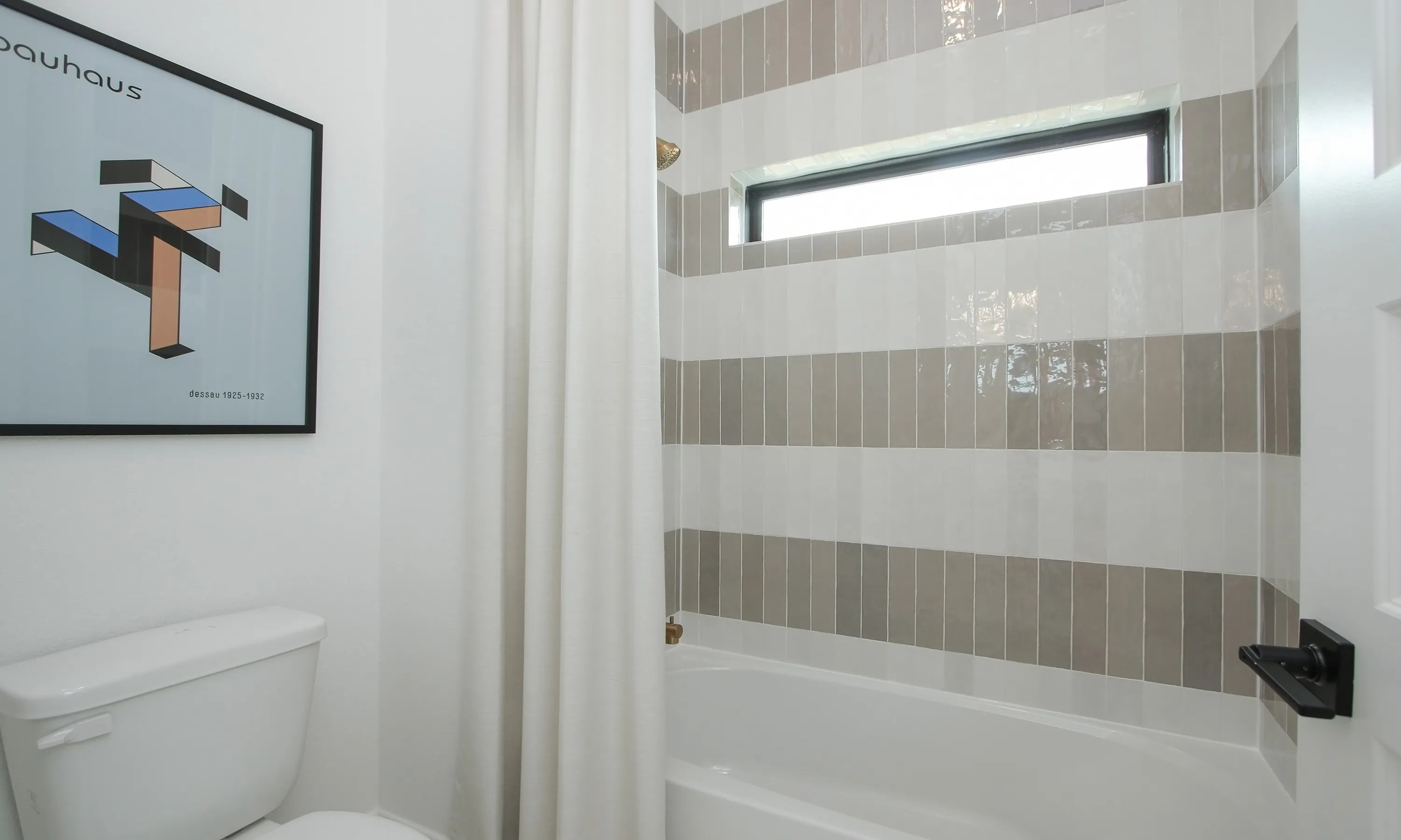 Modern bathroom with geometric art, beige and white striped tiles, Coastal Point community.