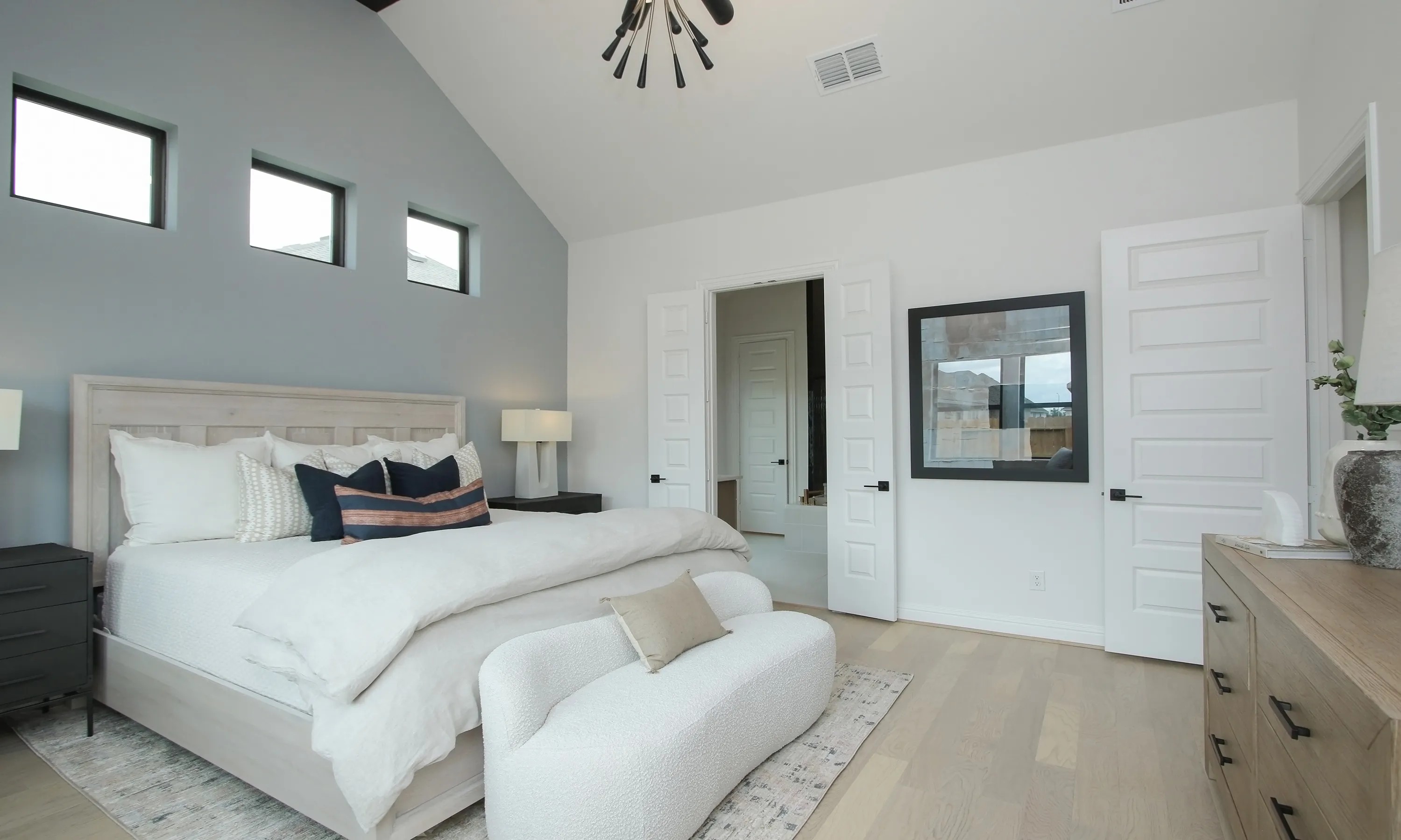 Luxurious bedroom in Coastal Point with vaulted ceiling, elegant lighting, and modern decor. Texas home.