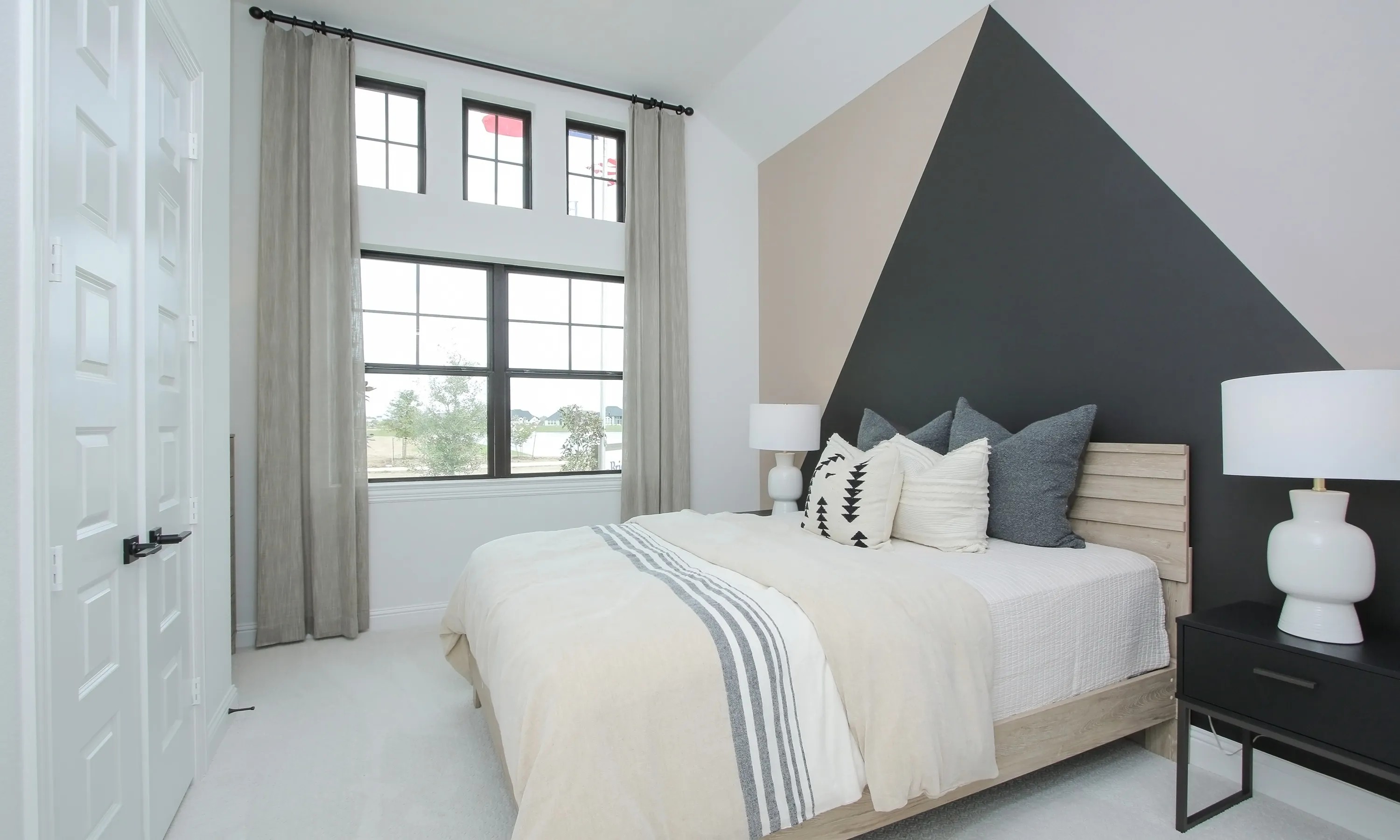 Modern bedroom with geometric accent wall and large windows in Coastal Point community.