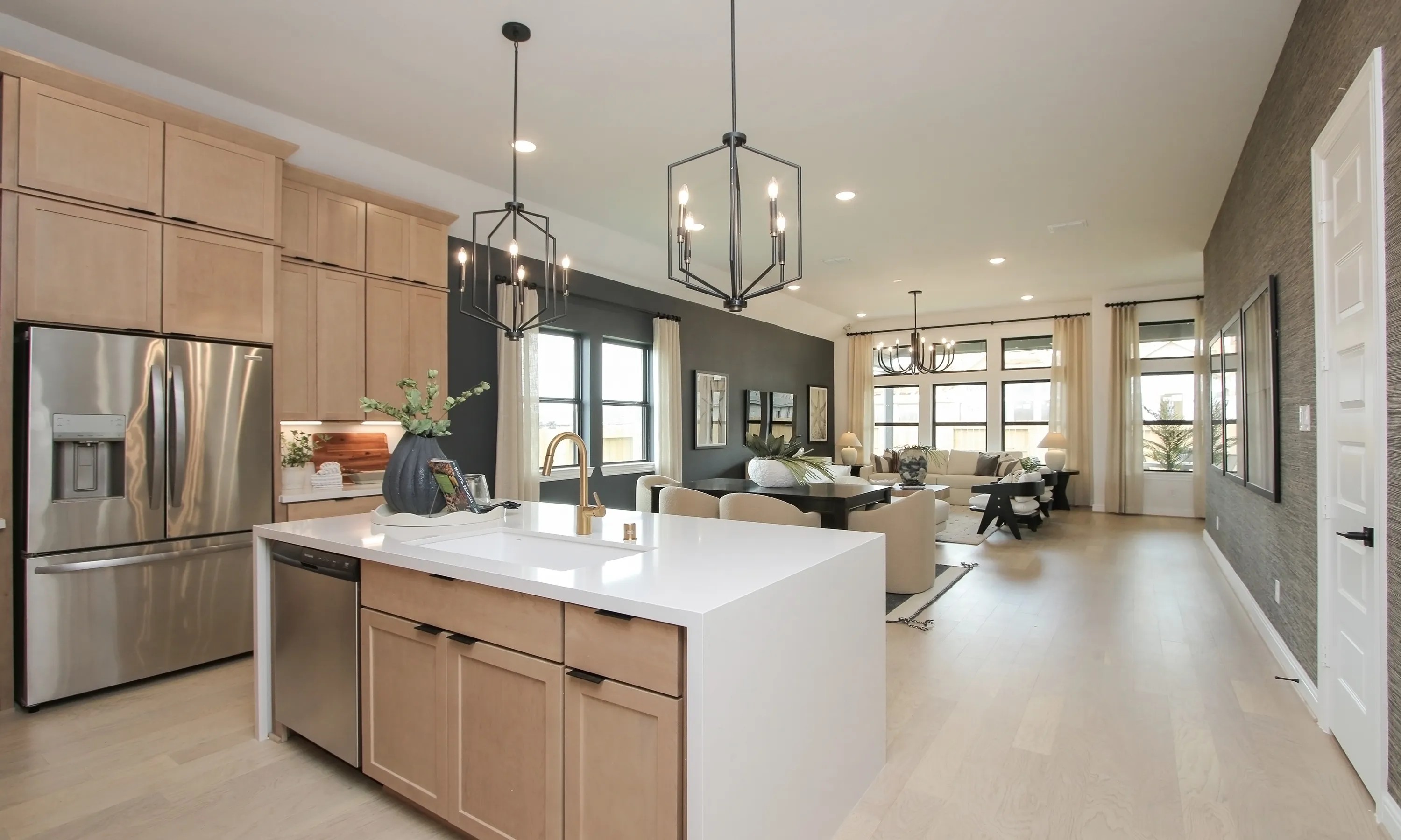 Modern kitchen and living area in upscale home, Coastal Point, large windows, light wood floors, sleek lighting.