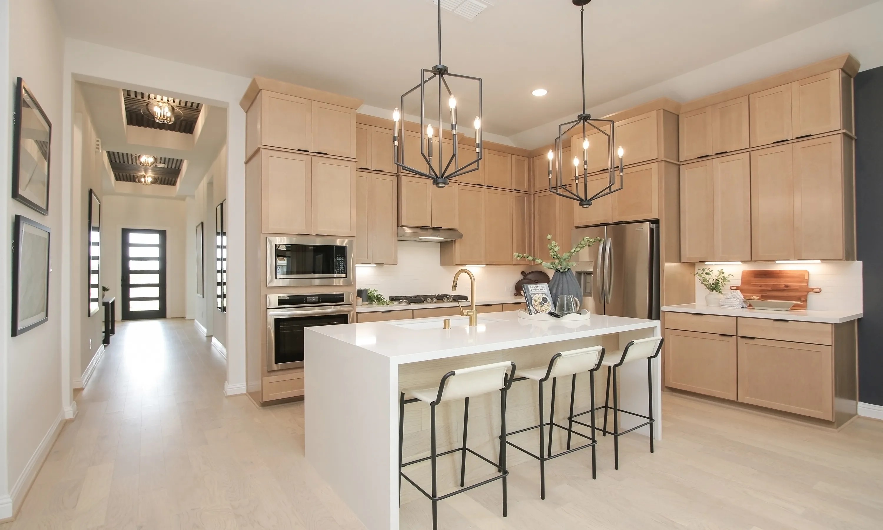 Modern kitchen, light wood cabinets, island with gold faucet, Coastal Point community, sleek design.