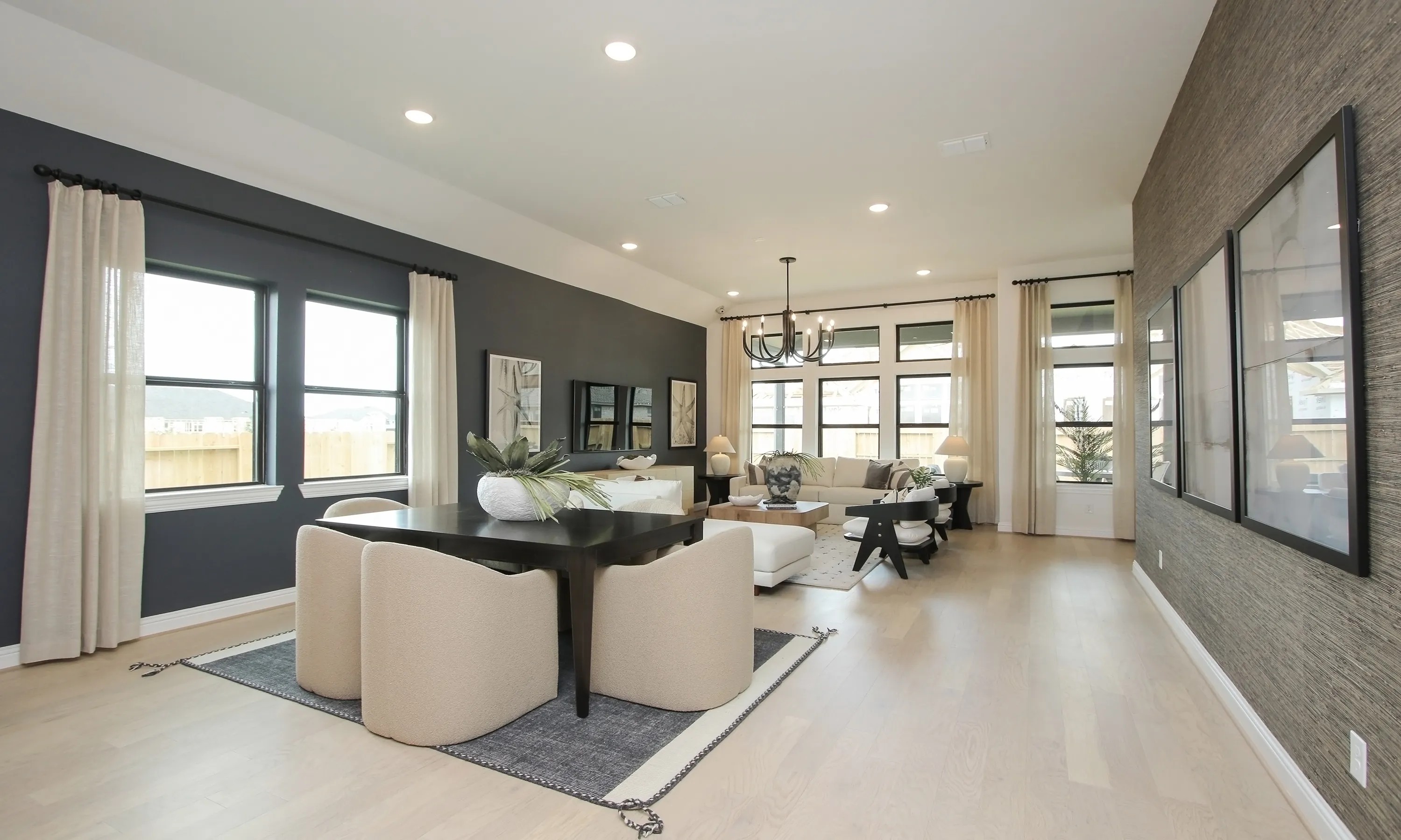 Spacious living room with chic decor, dark accent wall, large windows, and modern chandelier in Coastal Point.