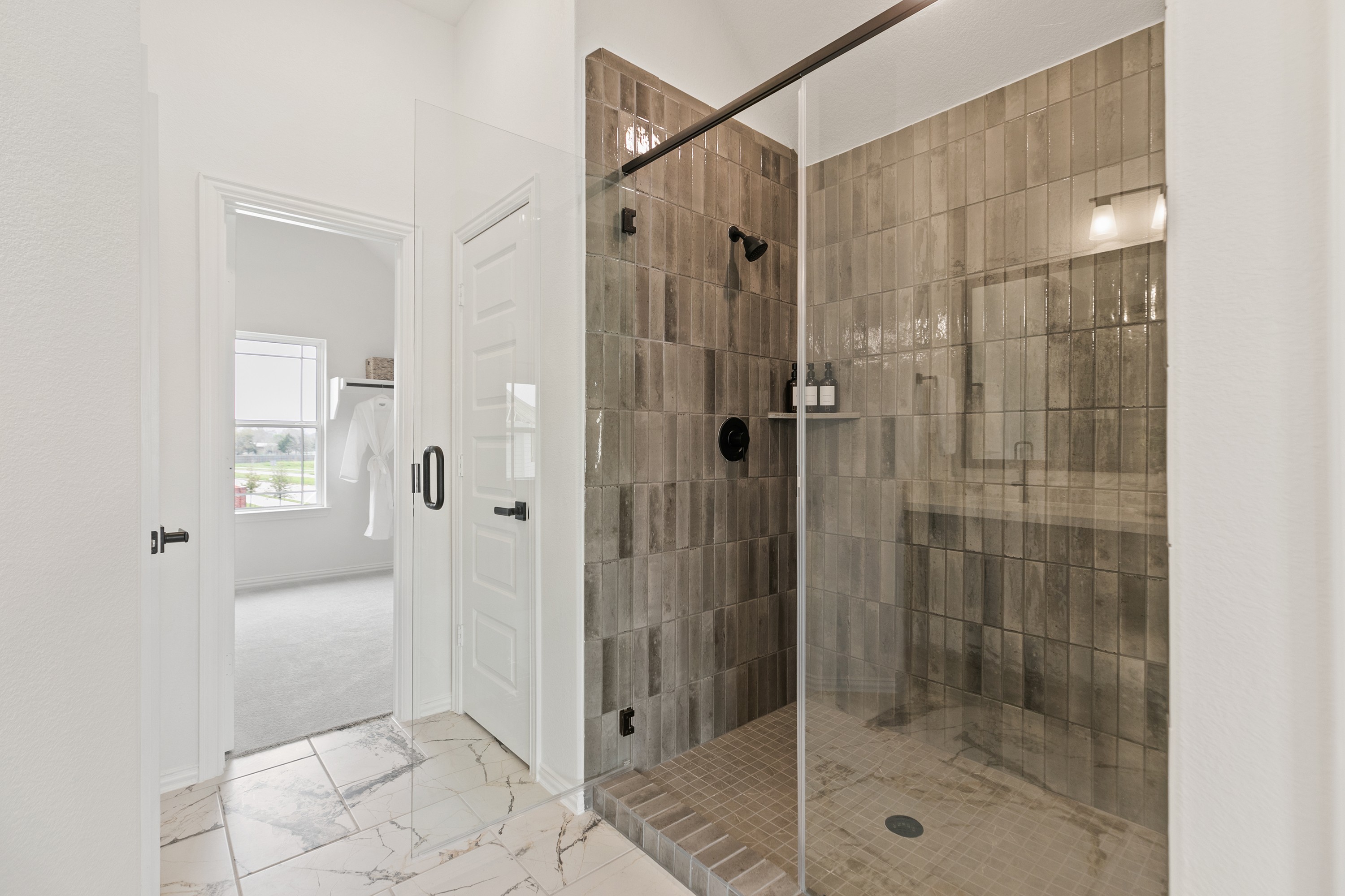 Modern shower with glass door and textured brown tiles in Park at Eldridge bathroom.