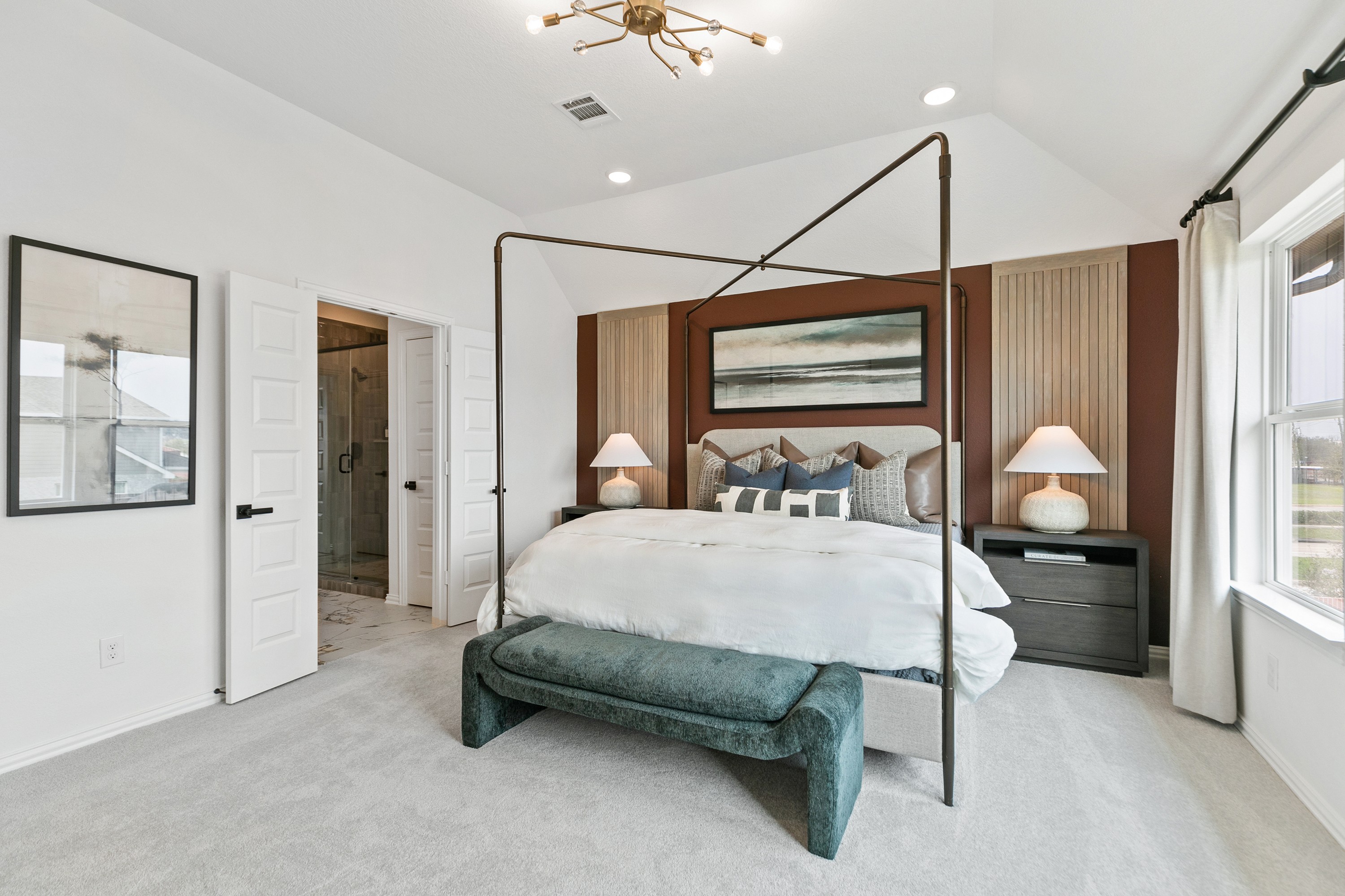 Elegant bedroom features a four-poster bed and chic lighting in Park at Eldridge, with a view of the outdoor landscape.