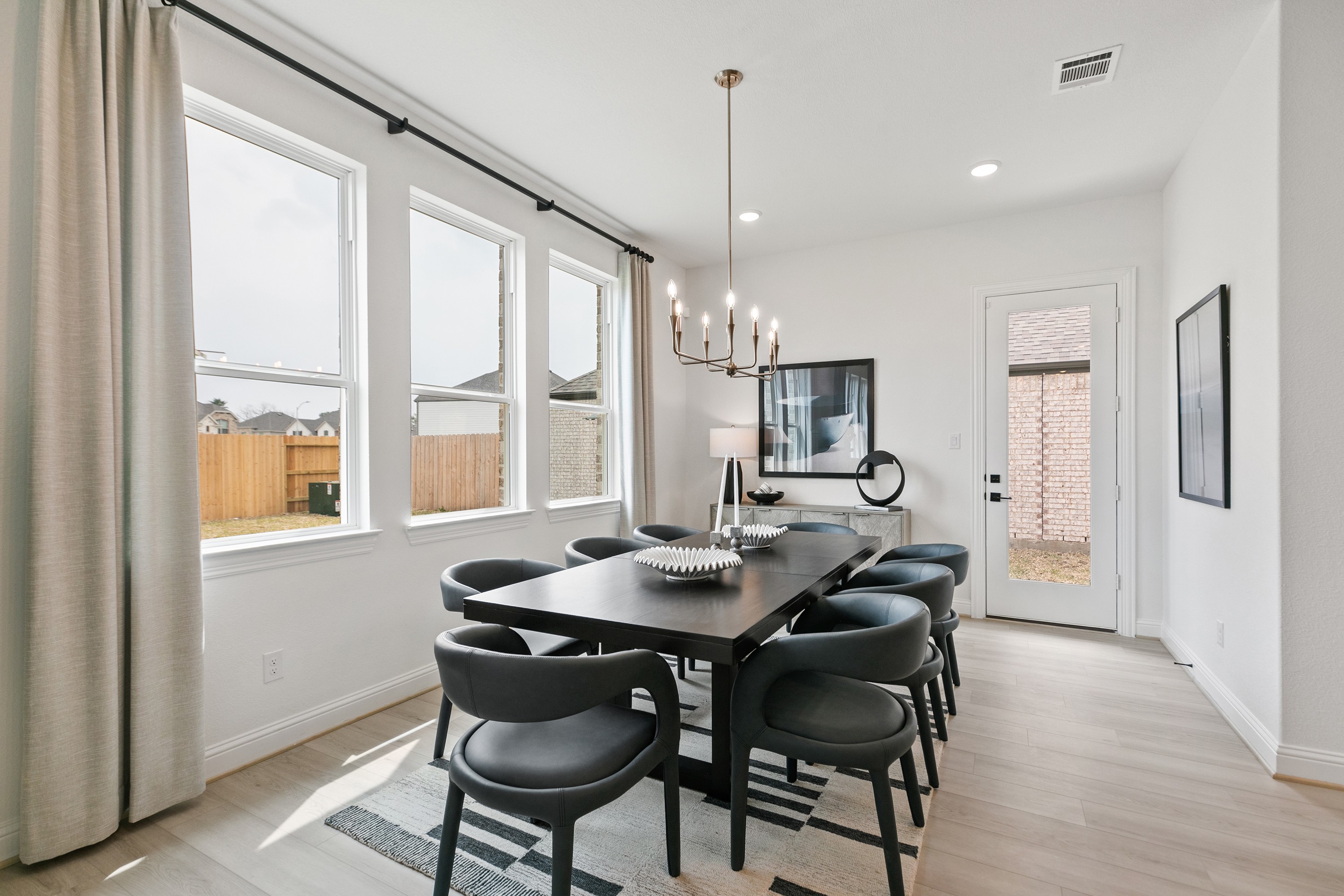 Elegant dining room with modern chandelier, large windows, and sleek furniture in Park at Eldridge, Houston.