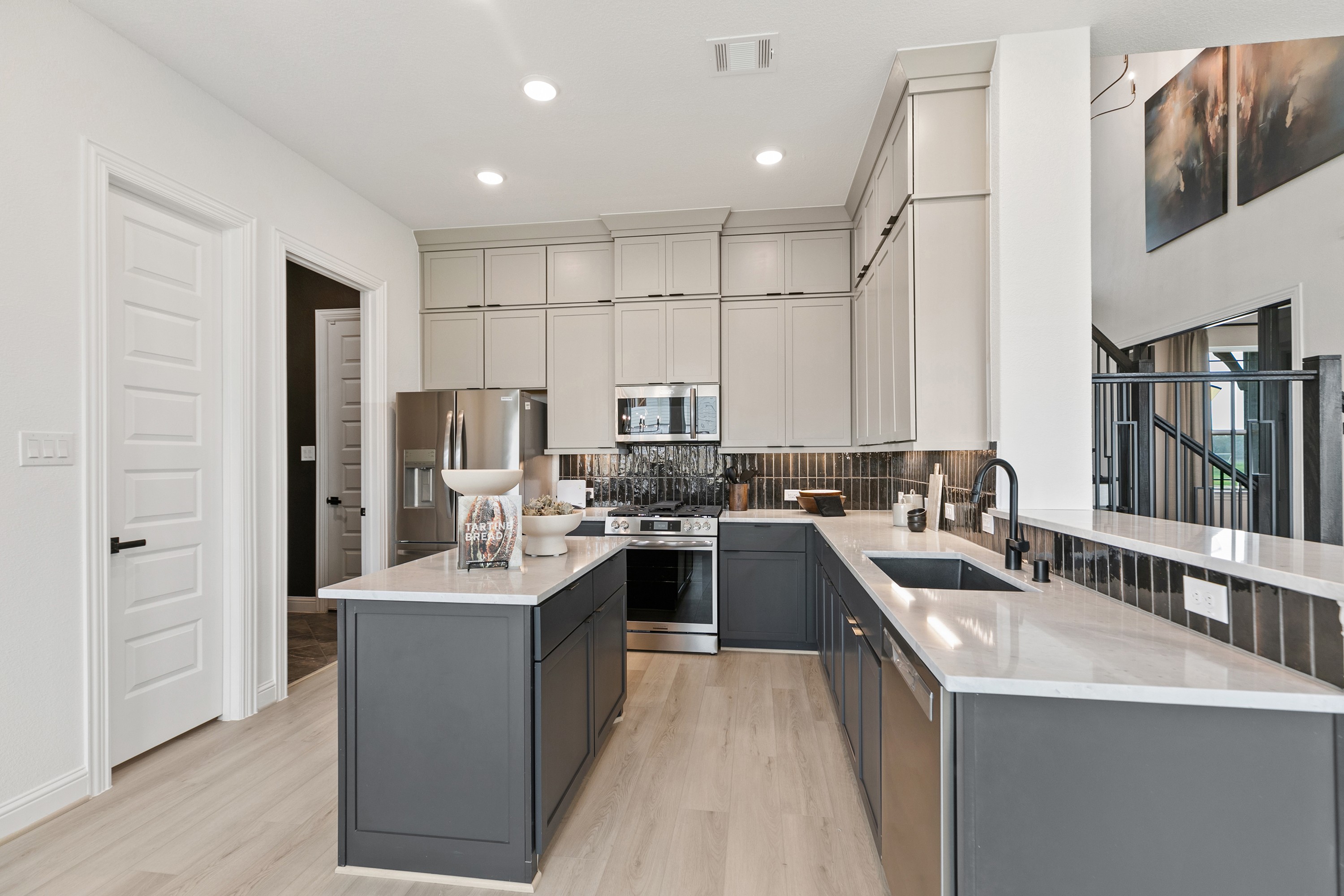 Modern kitchen with sleek cabinetry, marble countertops, and stainless appliances in Park at Eldridge, Houston luxury home.