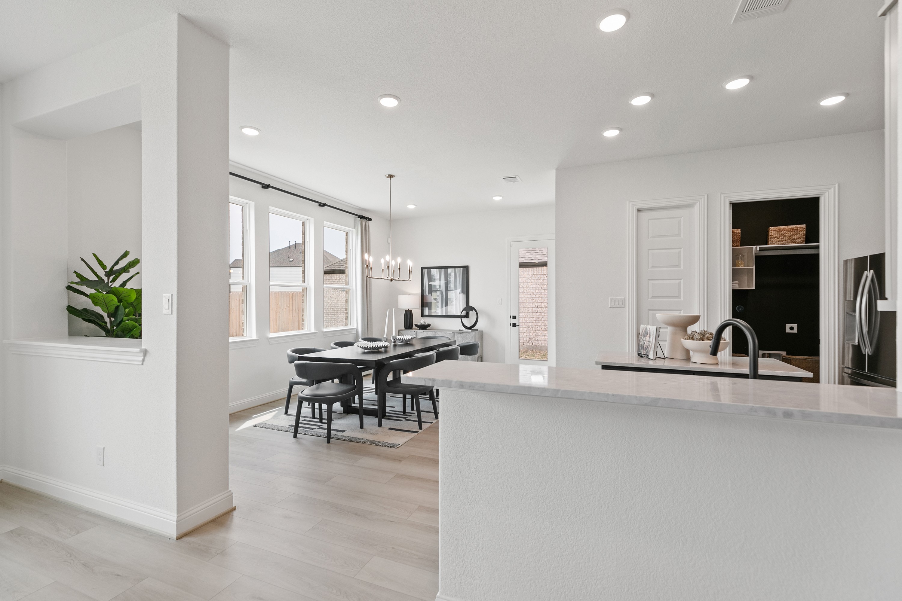Modern dining area with sleek chandelier, hardwood floor, and large windows in Park at Eldridge, Houston.