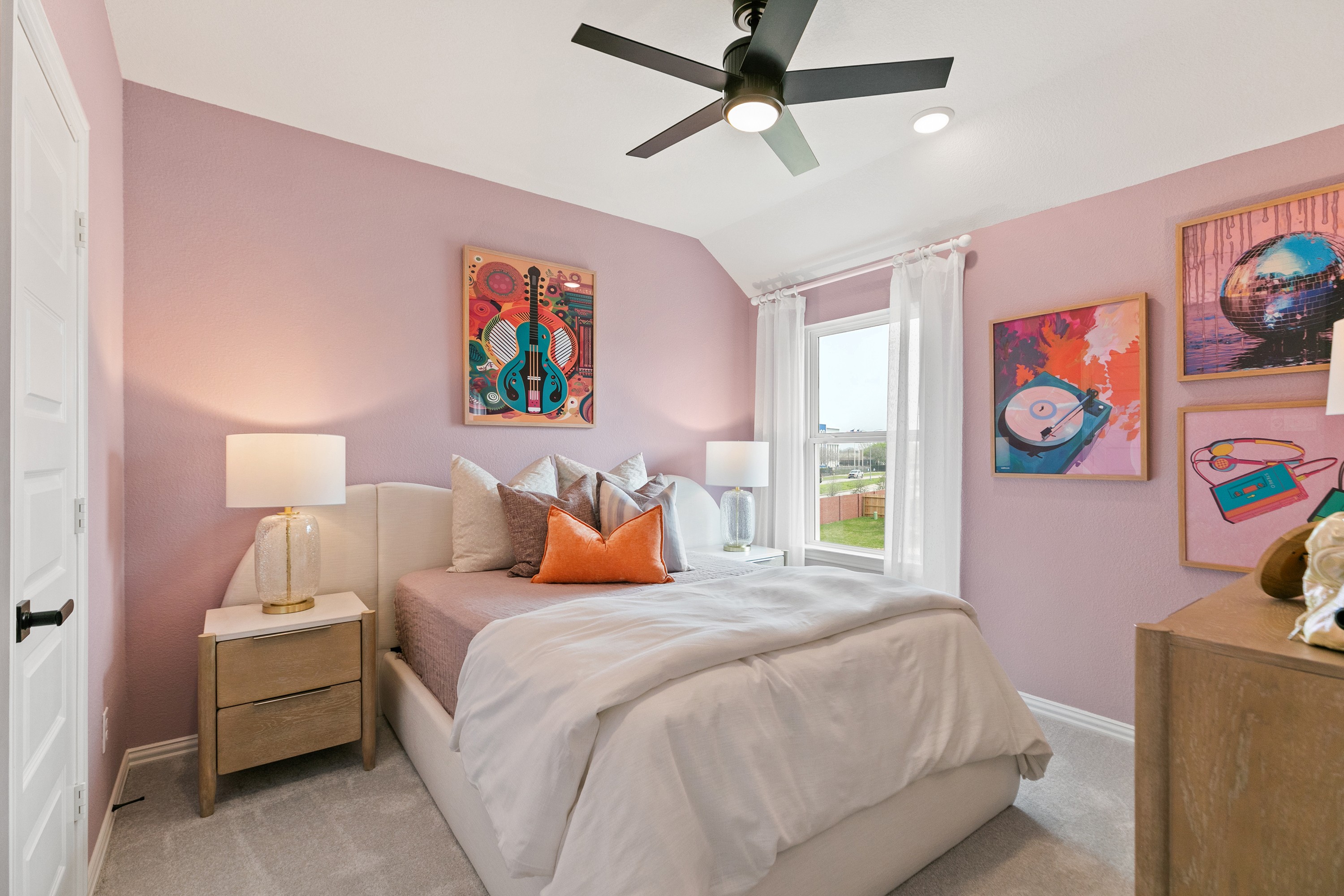 Bedroom features pastel pink walls, modern ceiling fan, large window, unique artwork. Park at Eldridge, Texas.