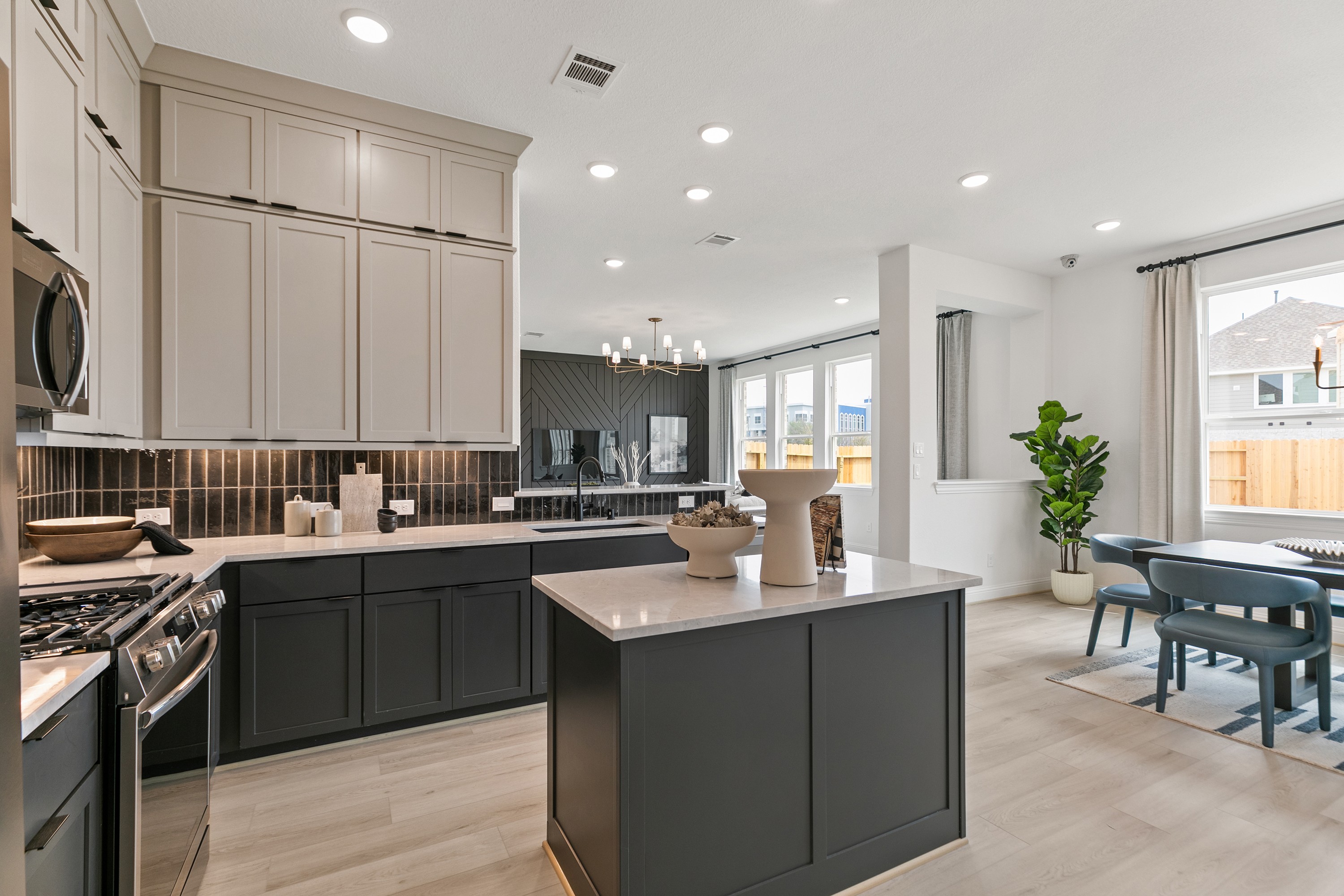 Modern kitchen in Park at Eldridge with quartz countertops, light wood floors, elegant cabinetry, large windows.