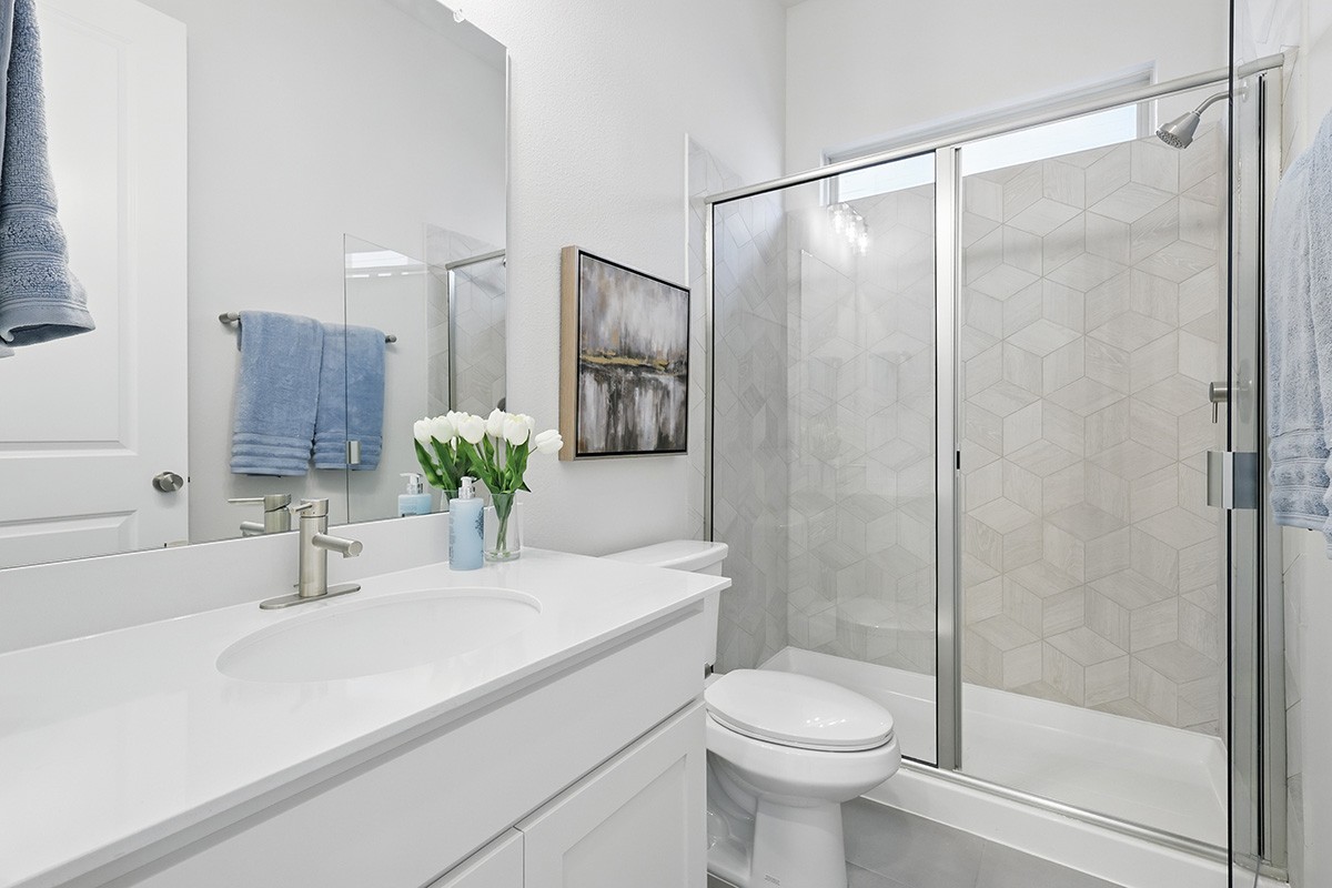 Luxurious modern bathroom in Green Meadows with geometric tile shower and sleek vanity.