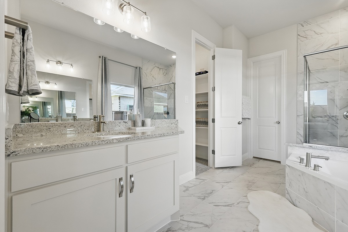 Modern bathroom with granite countertops, marble tile, chic lighting in Green Meadows community.