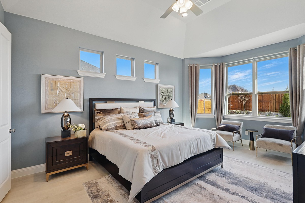 Elegant bedroom with high ceiling, large windows, and modern decor in Green Meadows community.