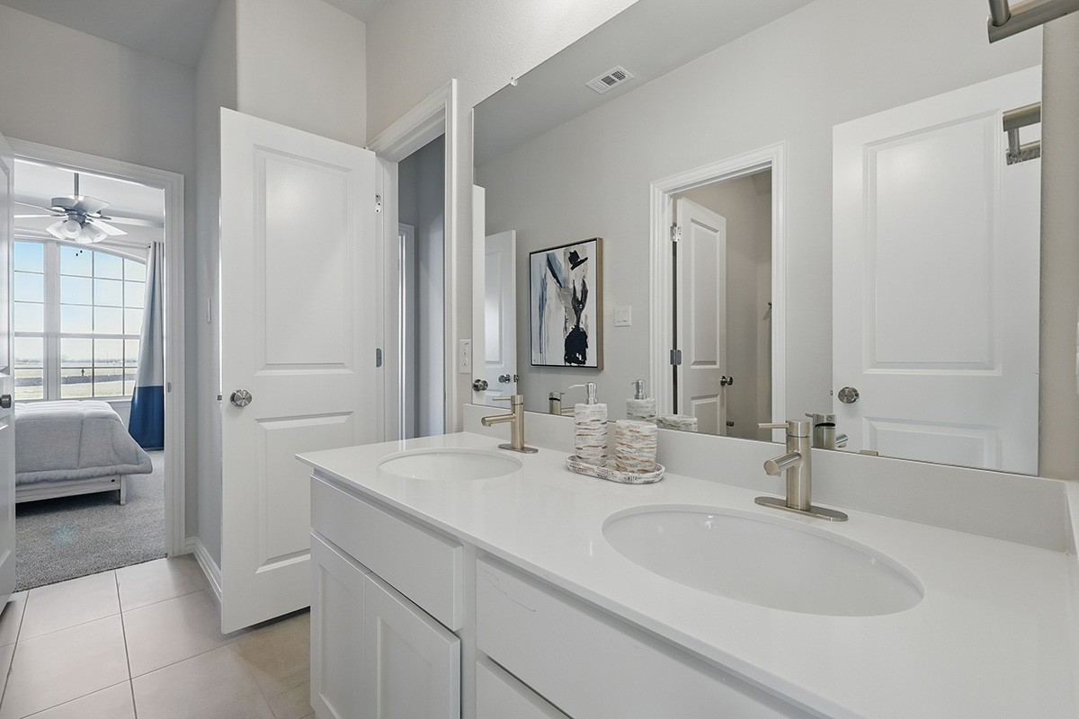 Modern bathroom with dual sinks and large mirror in Green Meadows home, featuring elegant fixtures.