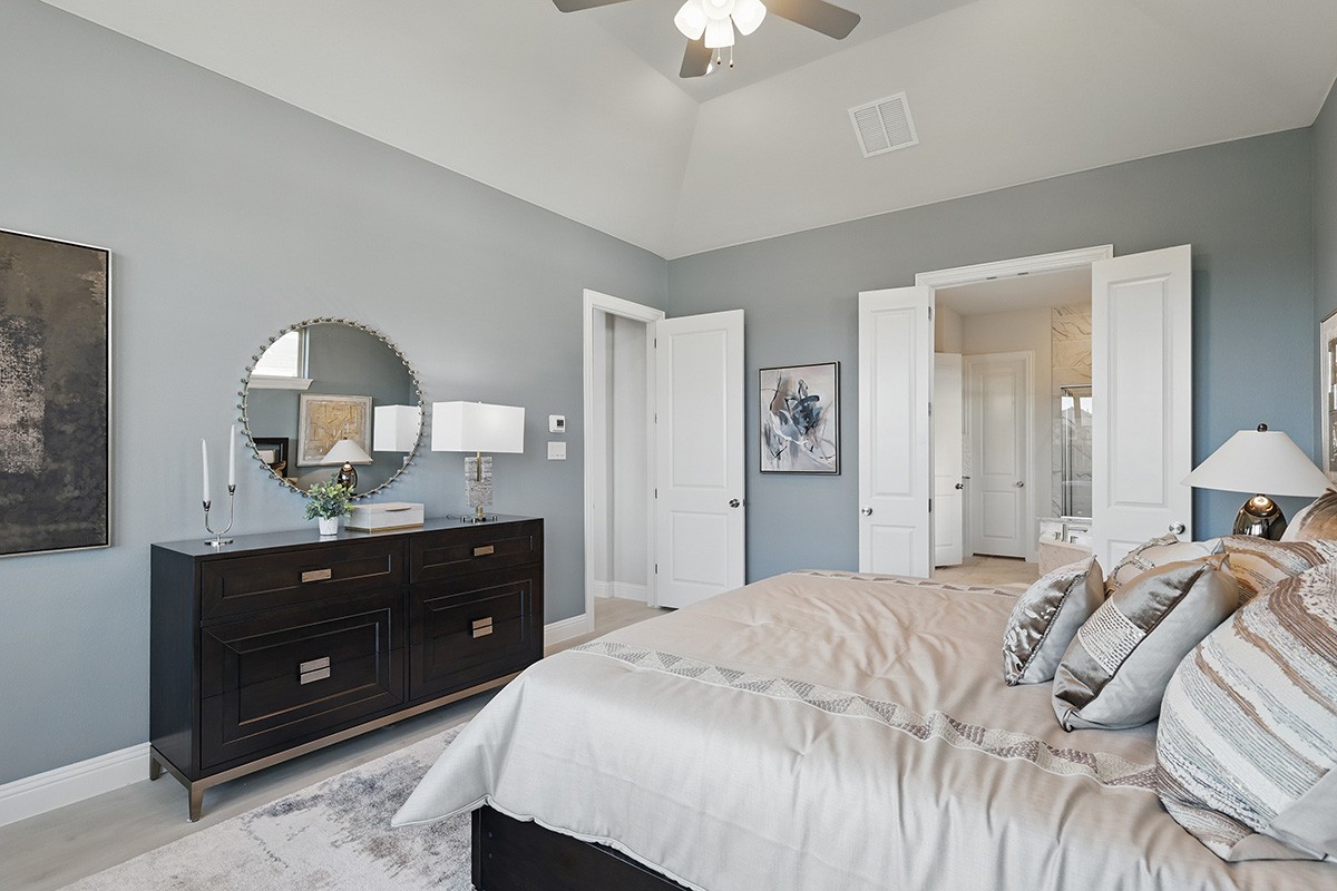 Elegant bedroom in Green Meadows, featuring vaulted ceiling, chic decor, modern dresser, and neutral palette.
