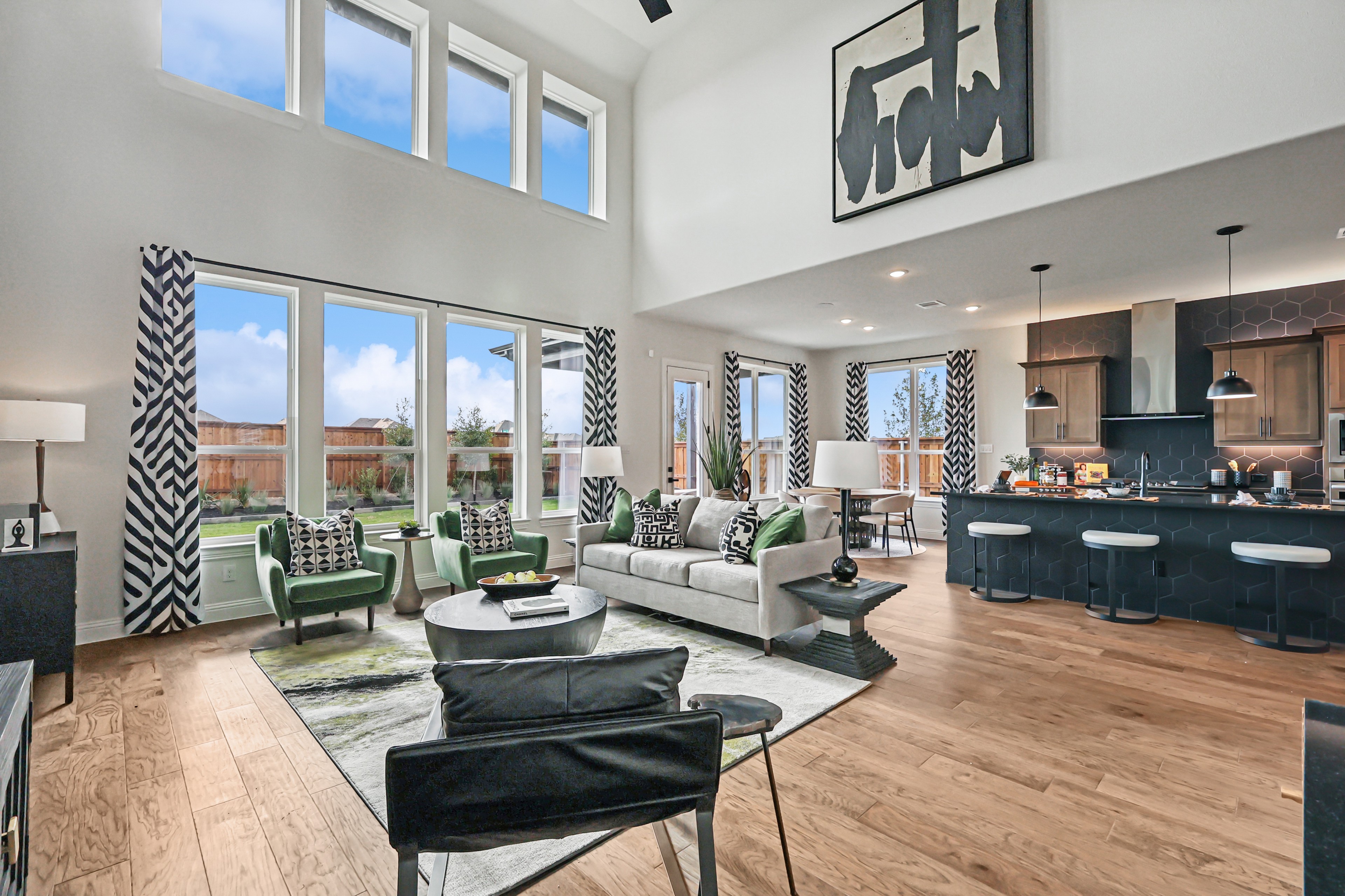 Modern living room with large windows, open floor plan, wood floors, and stylish decor in Green Meadows.