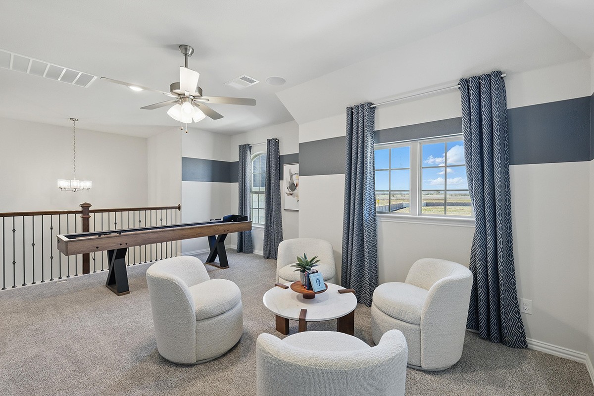 Modern game room with shuffleboard table, white chairs, and window view at Green Meadows. Elegant and spacious design.
