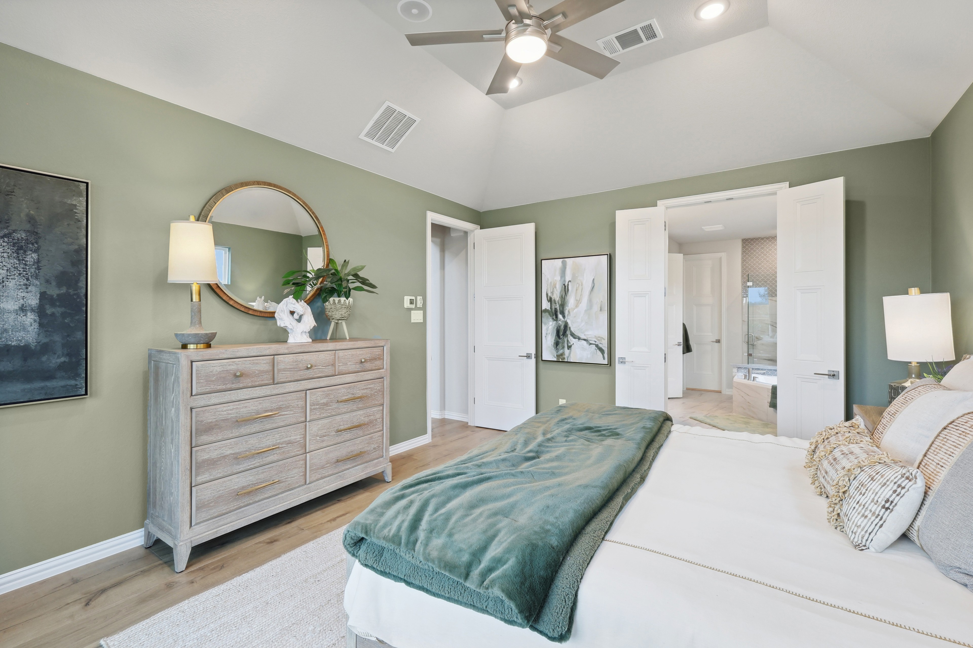Luxurious bedroom at Wildflower Ranch with vaulted ceiling, soft green walls, and elegant decor.