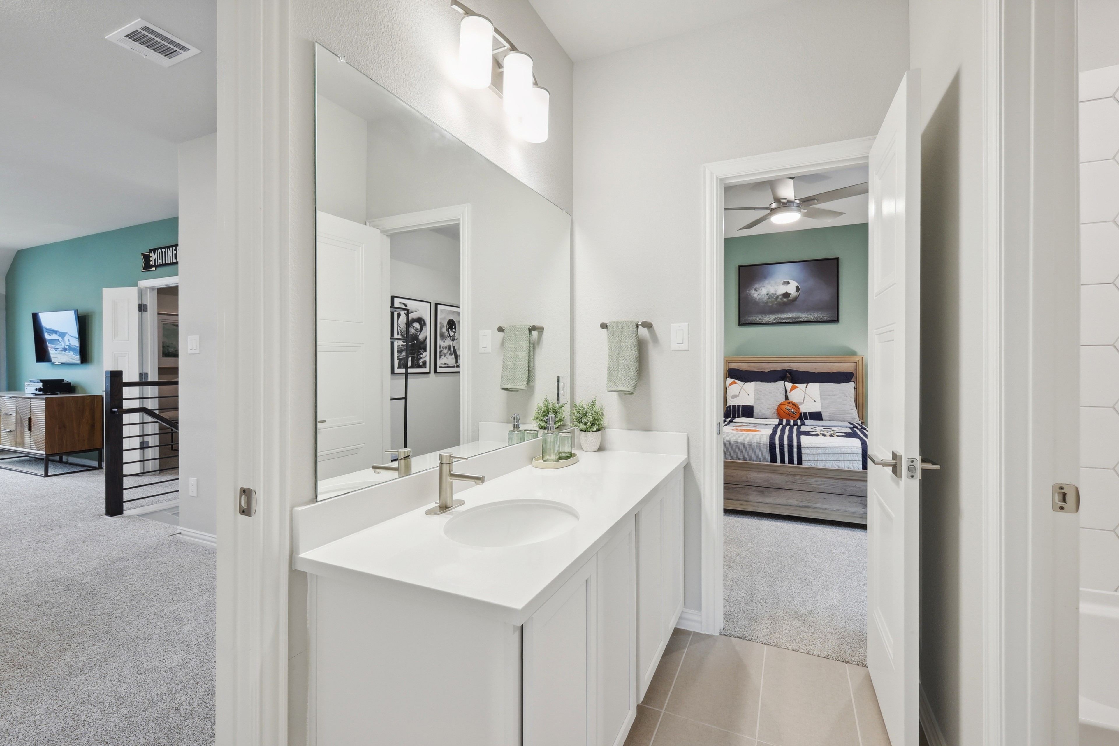 Elegant bathroom with white vanity, large mirror, leading to stylish bedroom in Wildflower Ranch home.