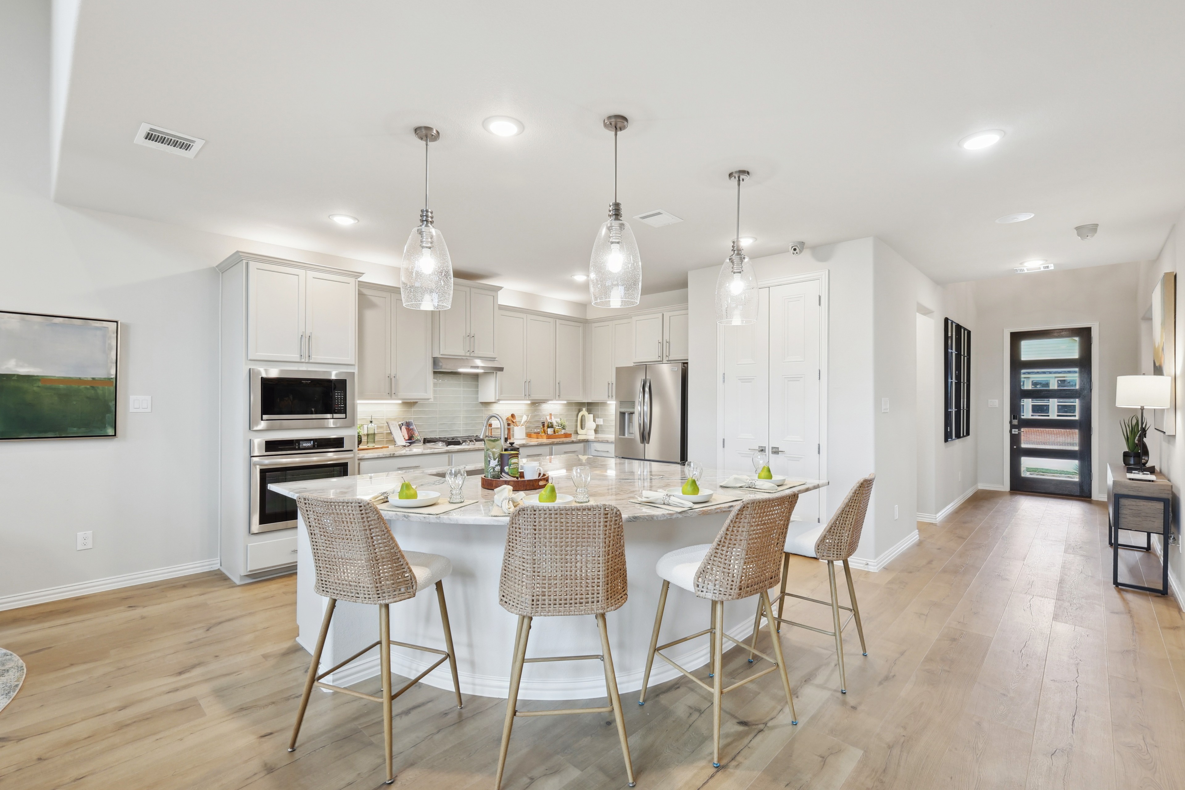 Luxury kitchen with marble island, pendant lights, and wicker stools in Wildflower Ranch.