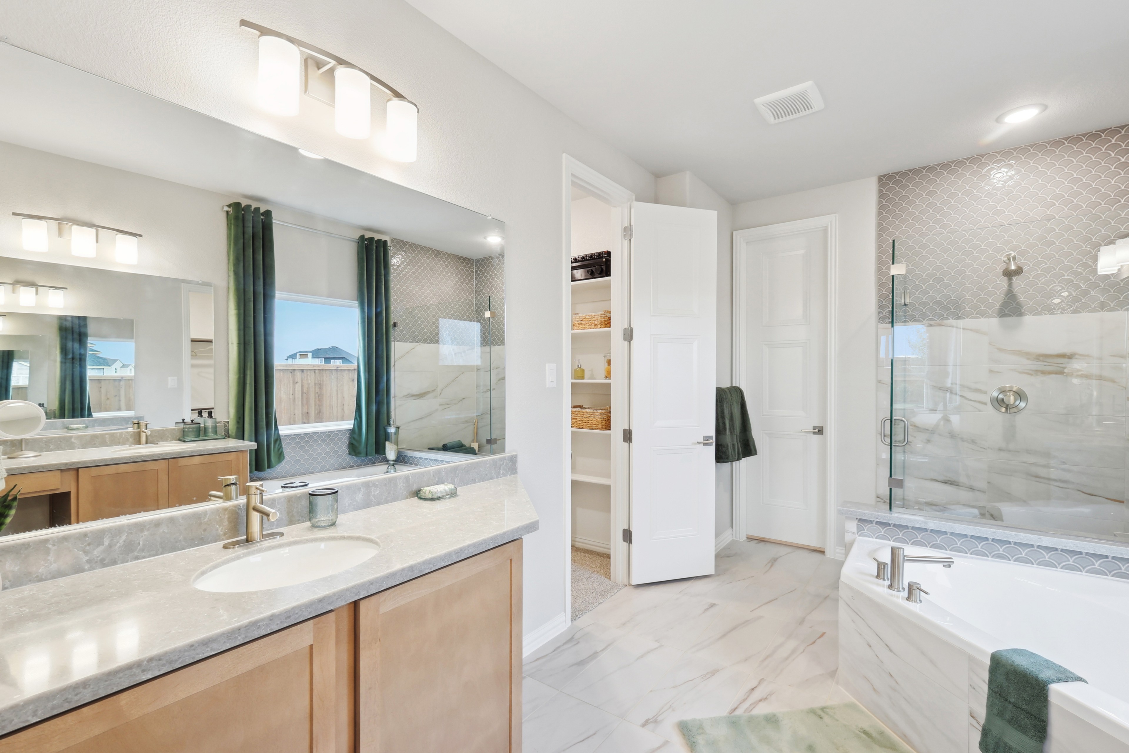 Luxurious bathroom with marble-tiled walls, spacious bathtub, large mirror, and green curtains at Wildflower Ranch.