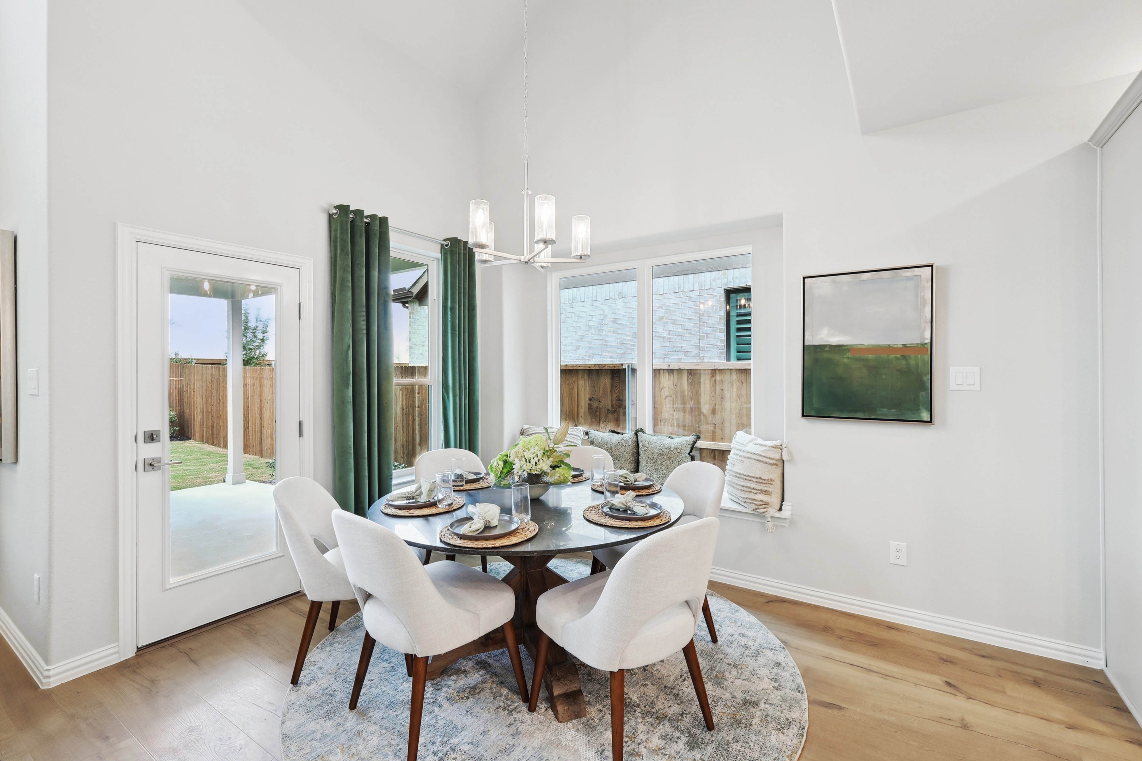 Elegant dining area with chic chandelier, round table, and plush chairs in Wildflower Ranch, Texas. Airy and bright.