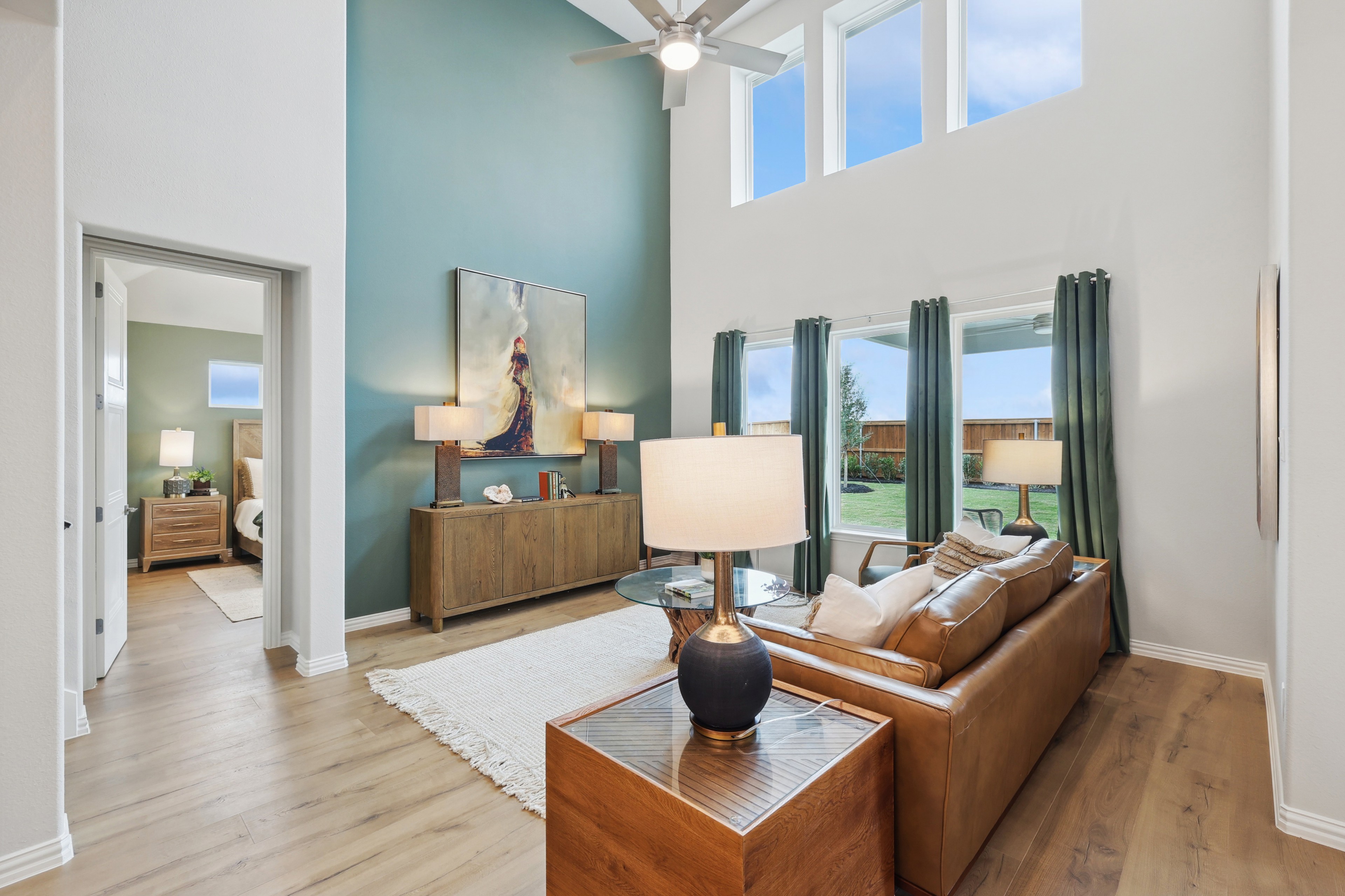 Spacious living room with high ceilings, modern decor, large windows, leather sofa, in Wildflower Ranch, Texas.