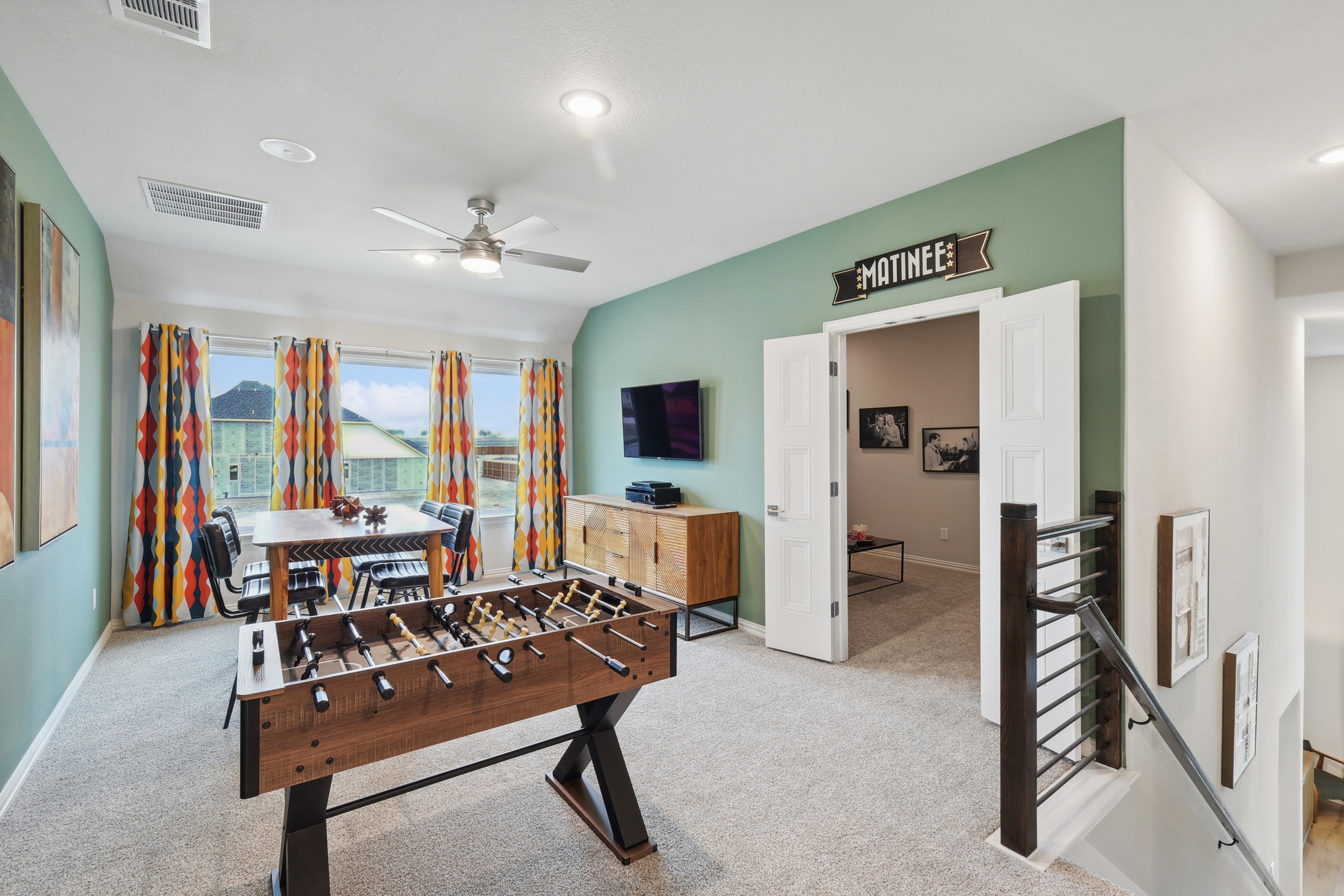 Game room with foosball, TV, green accent wall, colorful curtains, Wildflower Ranch.