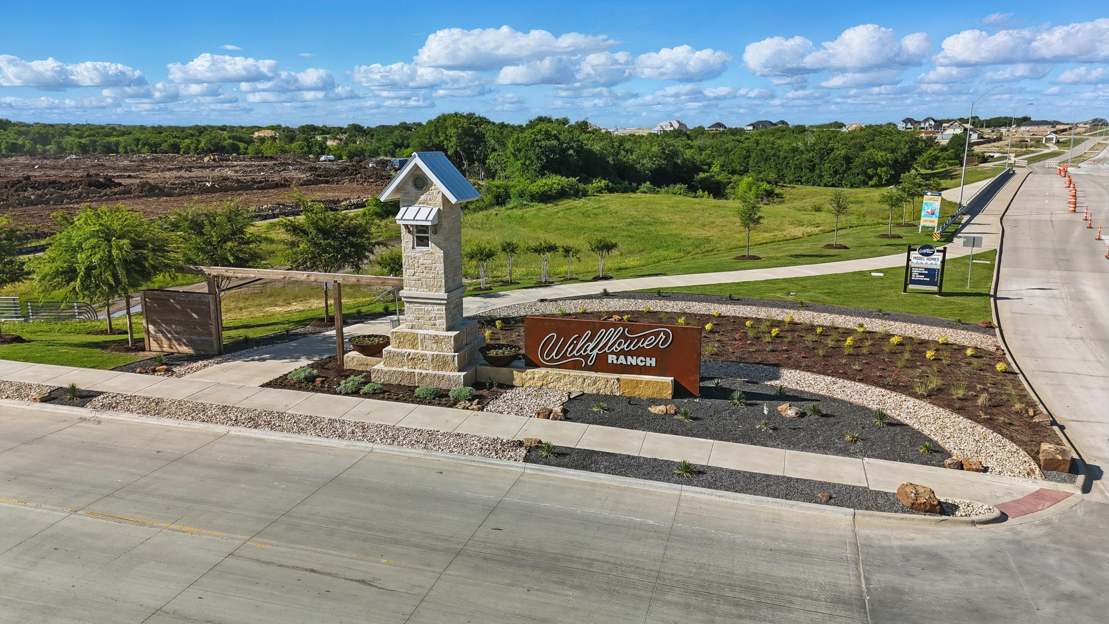 Entrance to Wildflower Ranch, Fort Worth; stone pillar, landscaping, clear skies, rural setting.