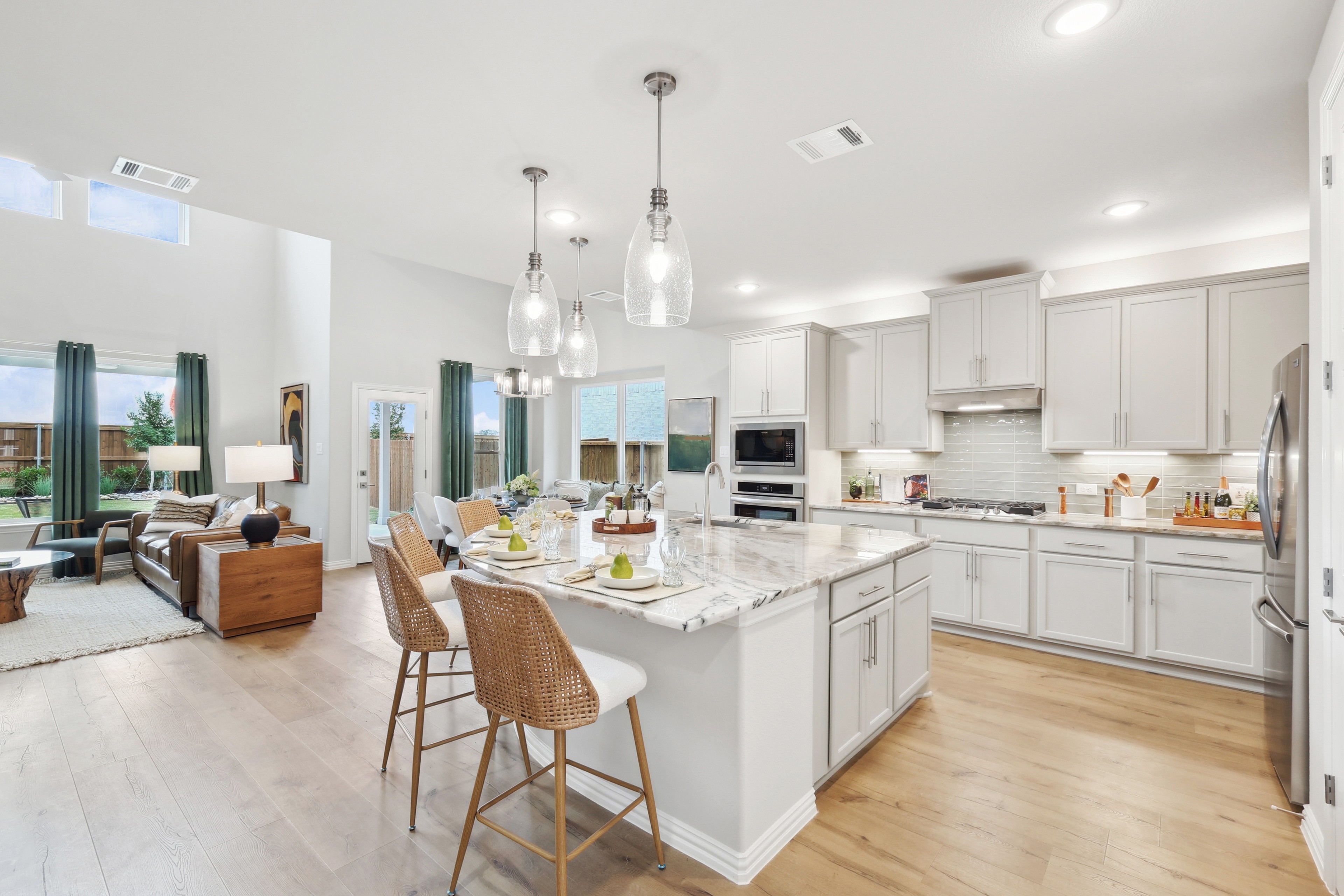 Spacious kitchen with marble island, modern pendant lights, and open layout in Wildflower Ranch community.