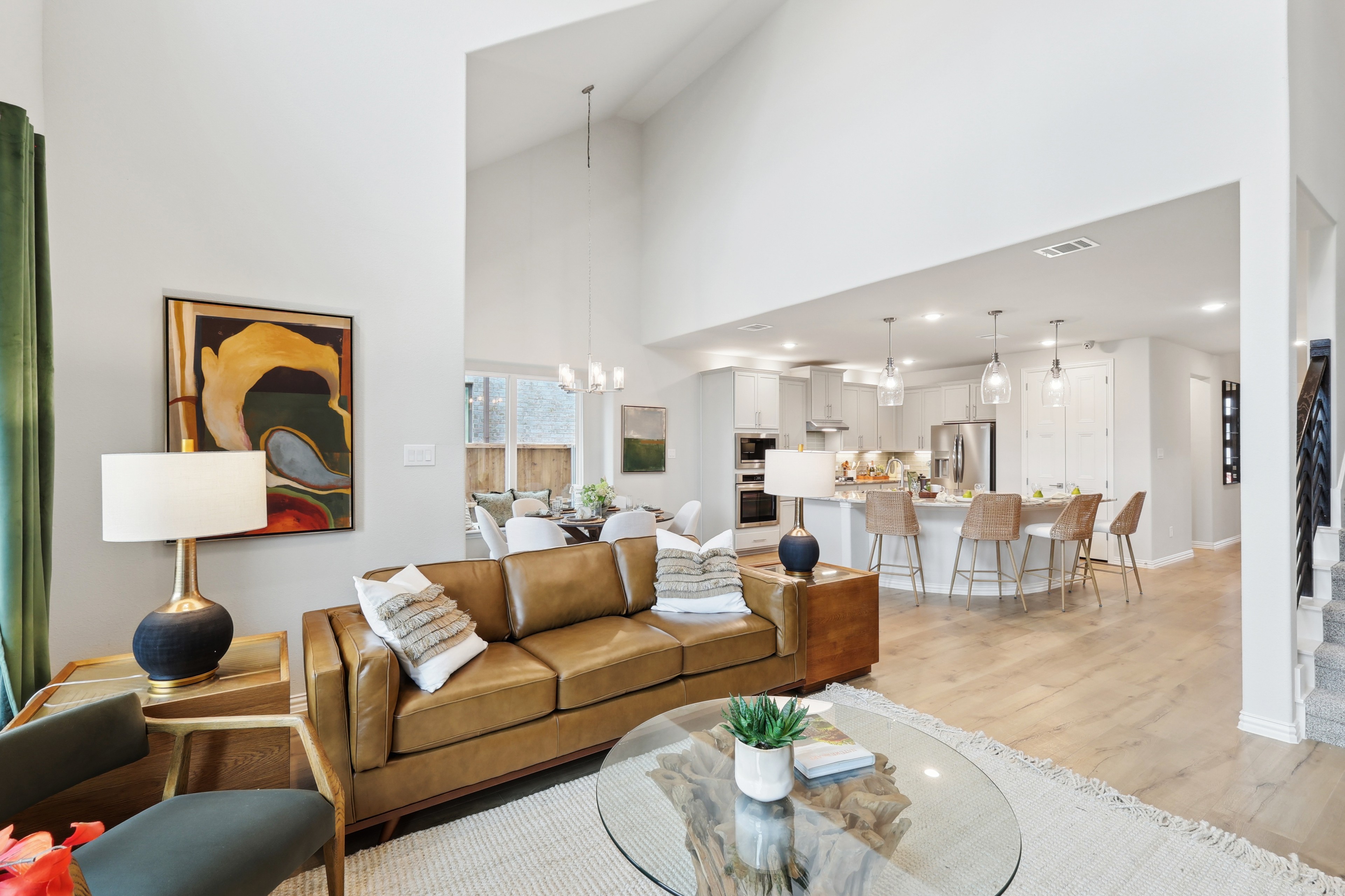 Stylish open-concept living area with vaulted ceiling, leather sofa, modern kitchen, in Wildflower Ranch.