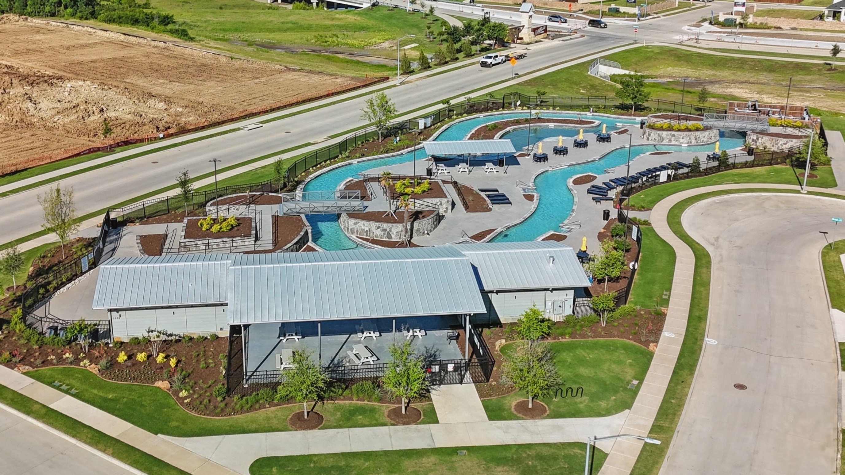 Aerial view of Wildflower Ranch community's leisure pool with modern pavilions and green landscaping, Texas.
