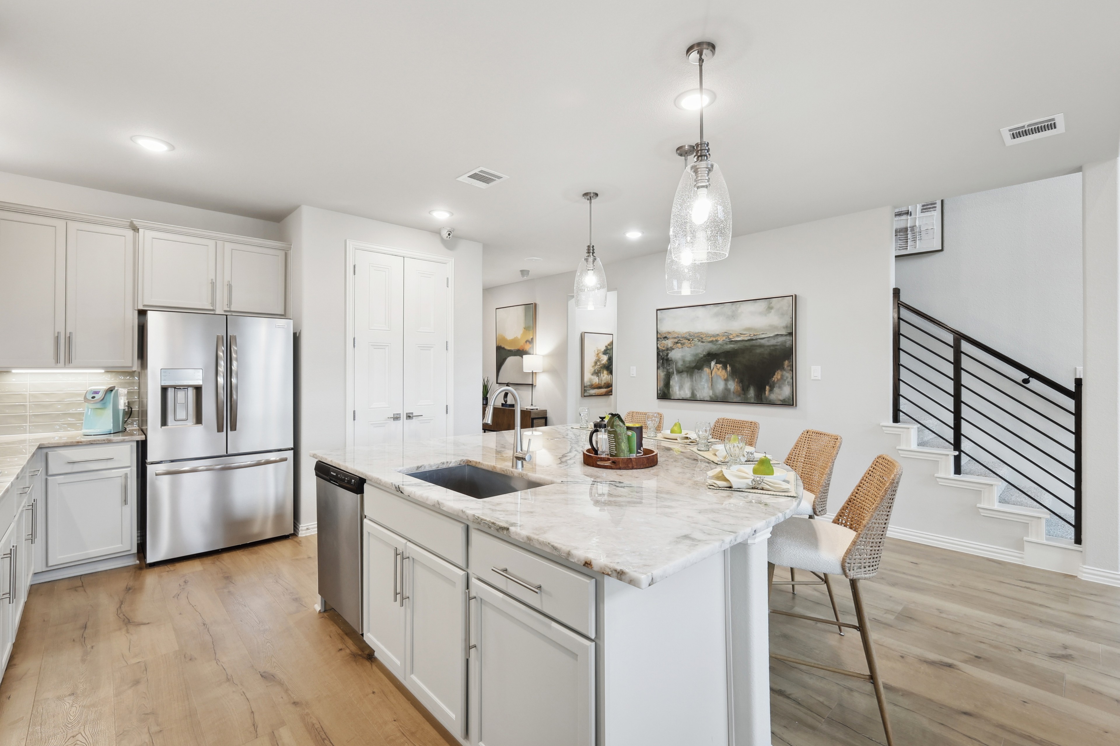 Modern kitchen with marble island, stainless appliances, elegant lighting; Wildflower Ranch community.