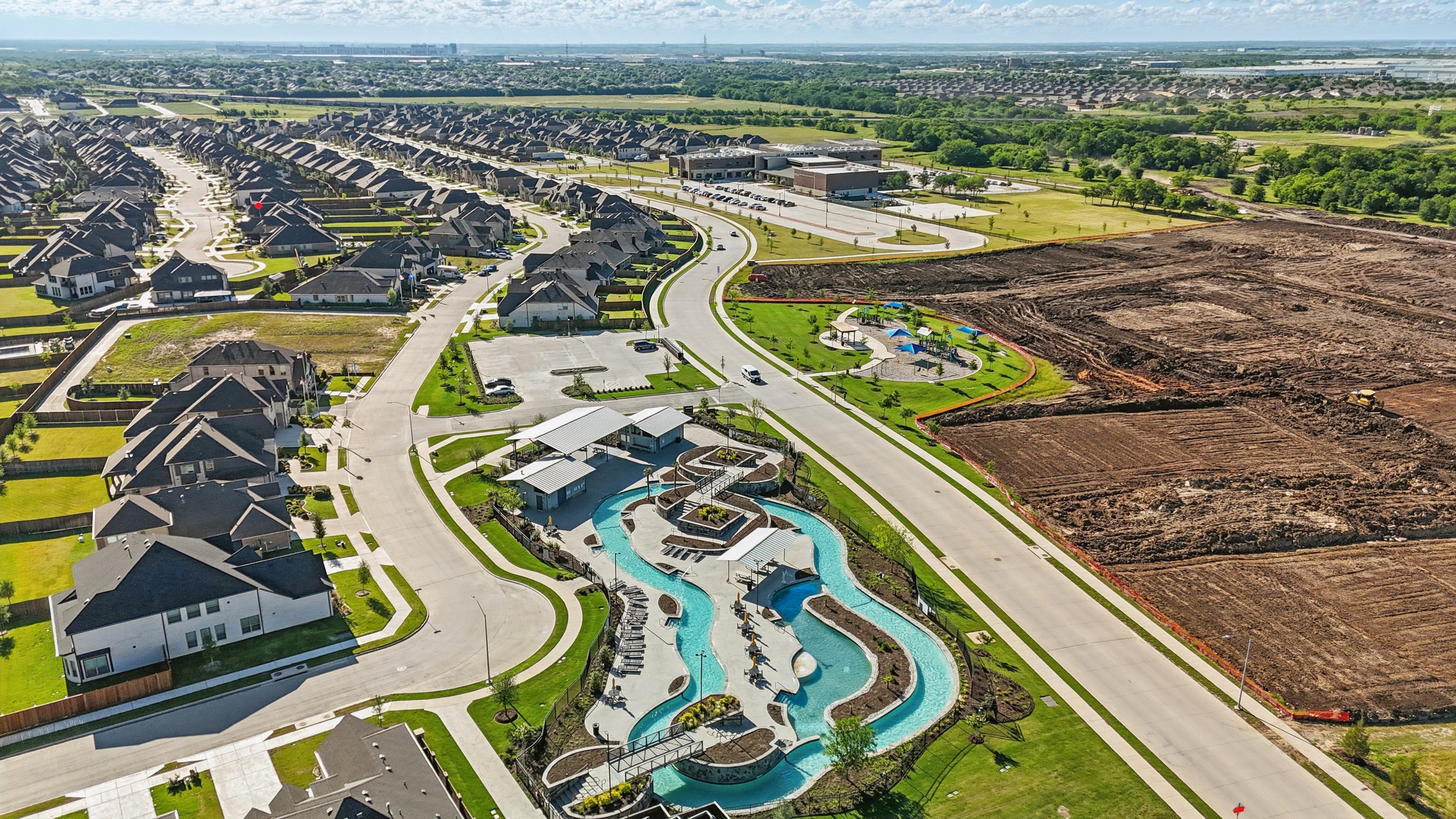 Luxury Wildflower Ranch aerial view, featuring winding roads, modern homes, community pool, park, and open land. Texas.