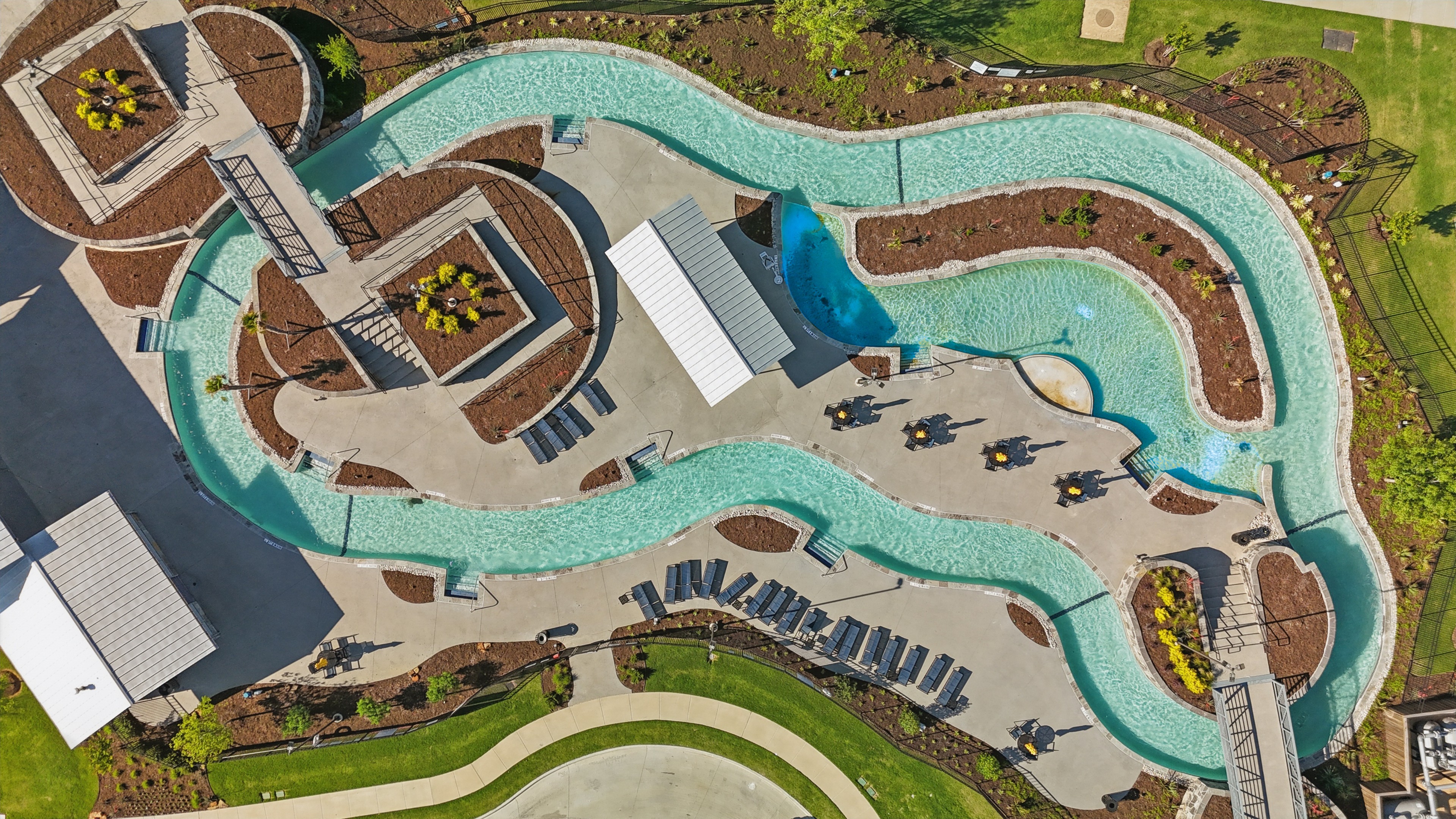 Aerial view of a winding lazy river with modern landscaping at Wildflower Ranch, Texas.