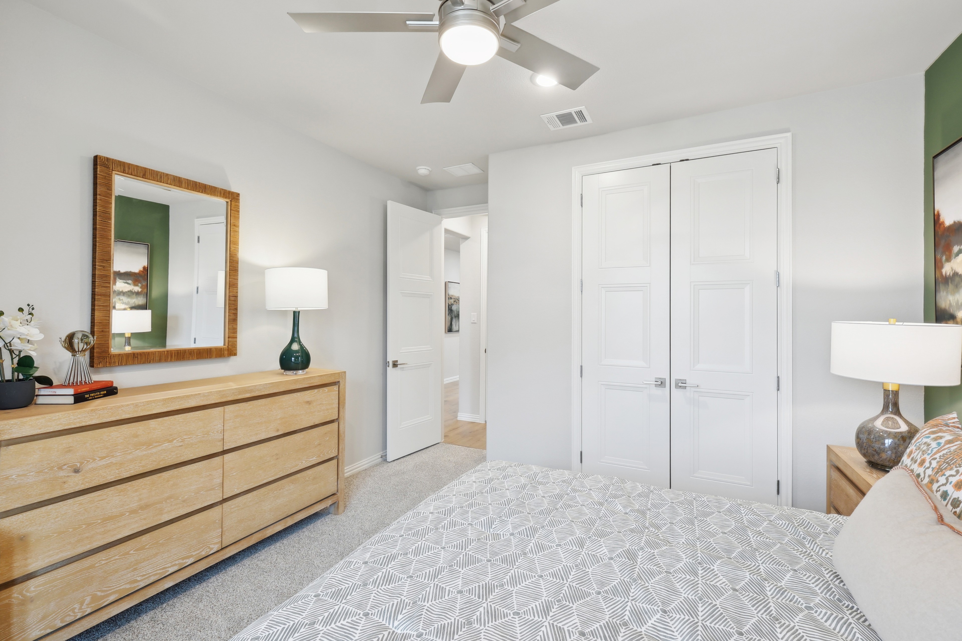 Modern bedroom, wood dresser, mirror, ceiling fan, green accent wall, Wildflower Ranch, light-filled, door.