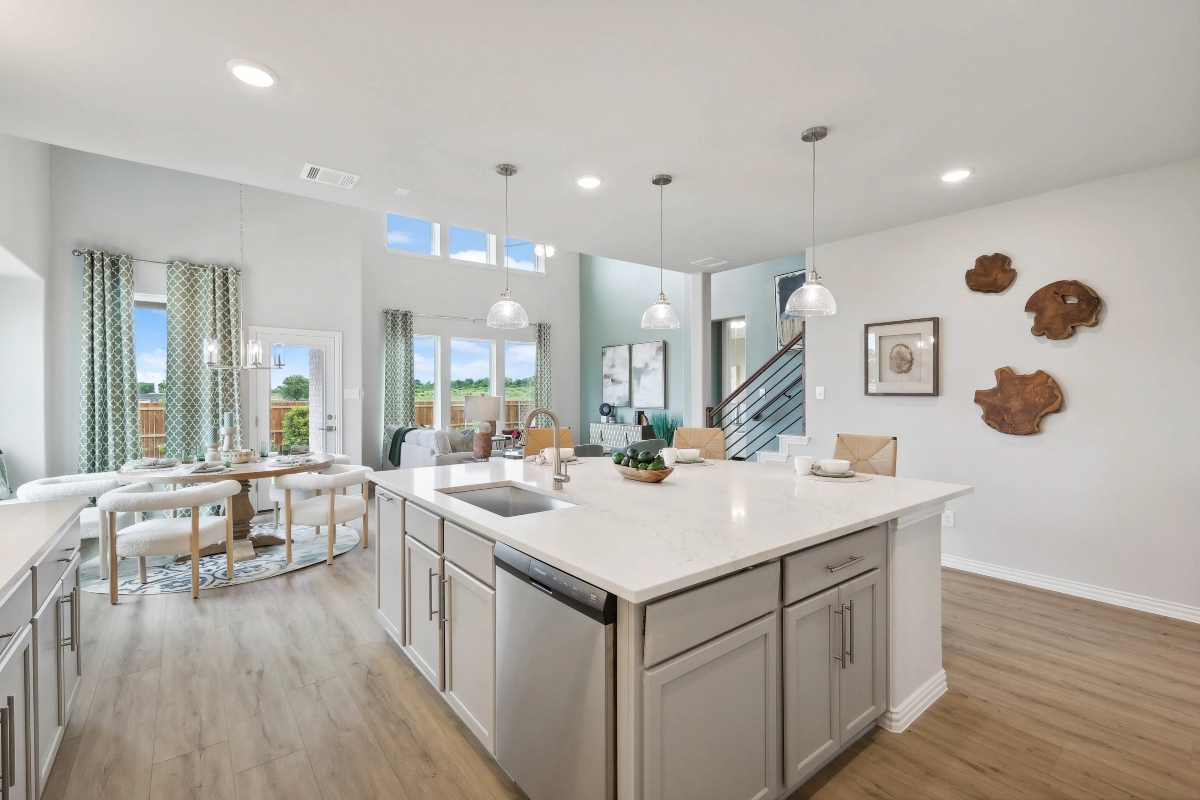 Modern kitchen with marble island, pendant lights, and hardwood floors in Hulen Trails home, Fort Worth.