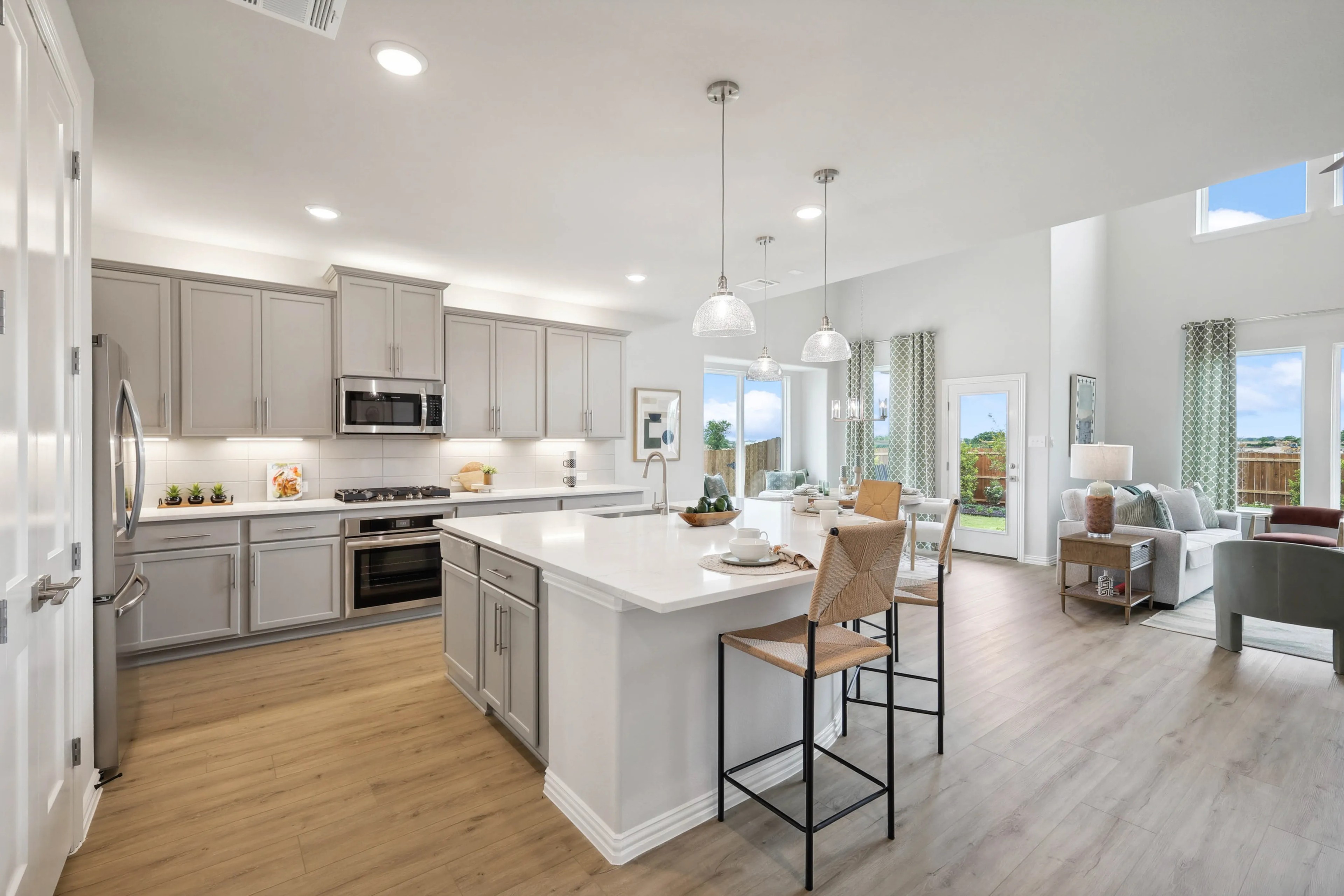 Modern kitchen with light gray cabinets, large white island, open floor plan in Hulen Trails, Fort Worth, Texas.