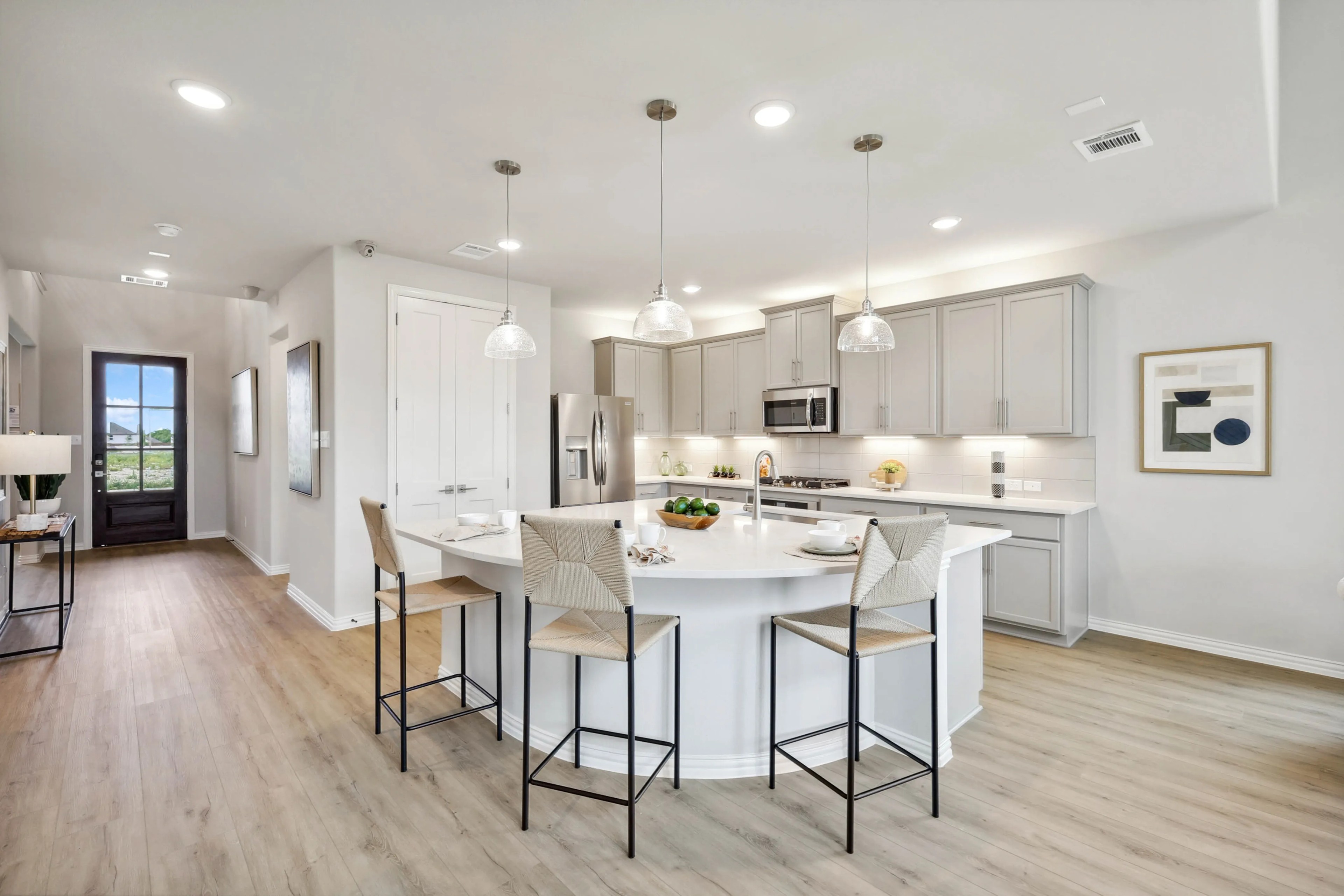Modern kitchen with island, pendant lights, gray cabinets, wood floor. Hulen Trails, Fort Worth.