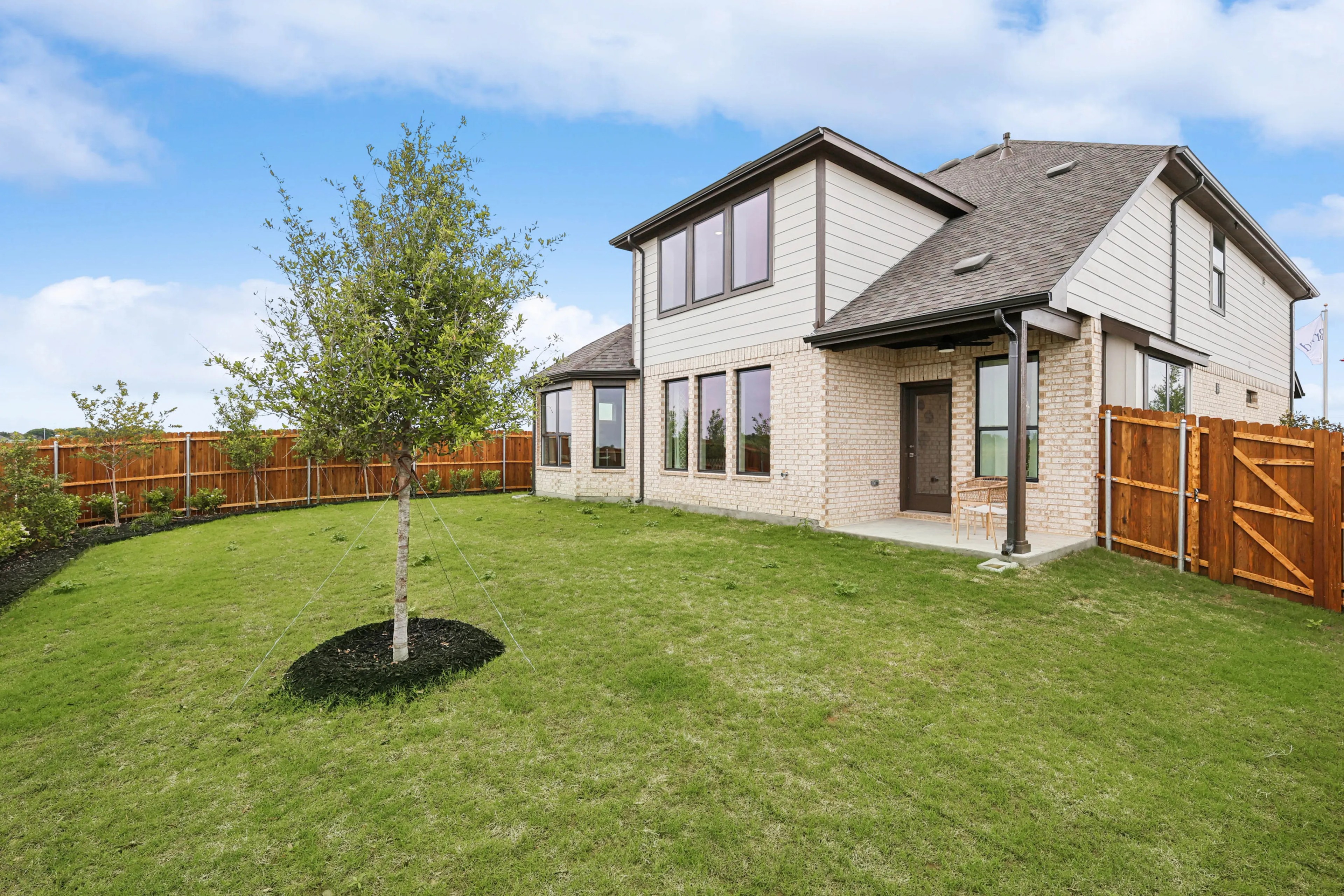 Two-story brick house in Hulen Trails with large windows, patio, and landscaped yard.