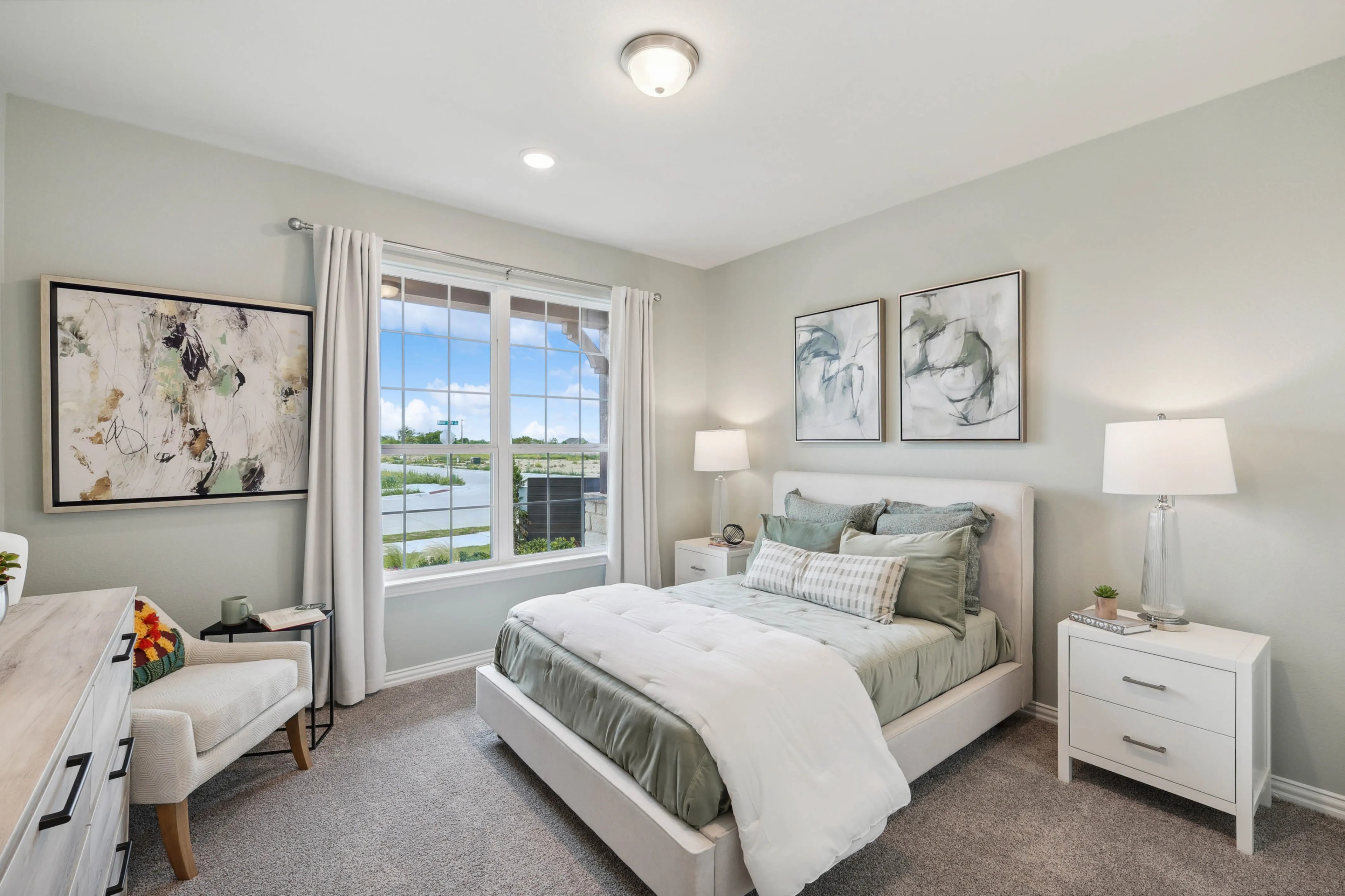 Elegant bedroom with large window, abstract art, and plush bedding in Hulen Trails community.