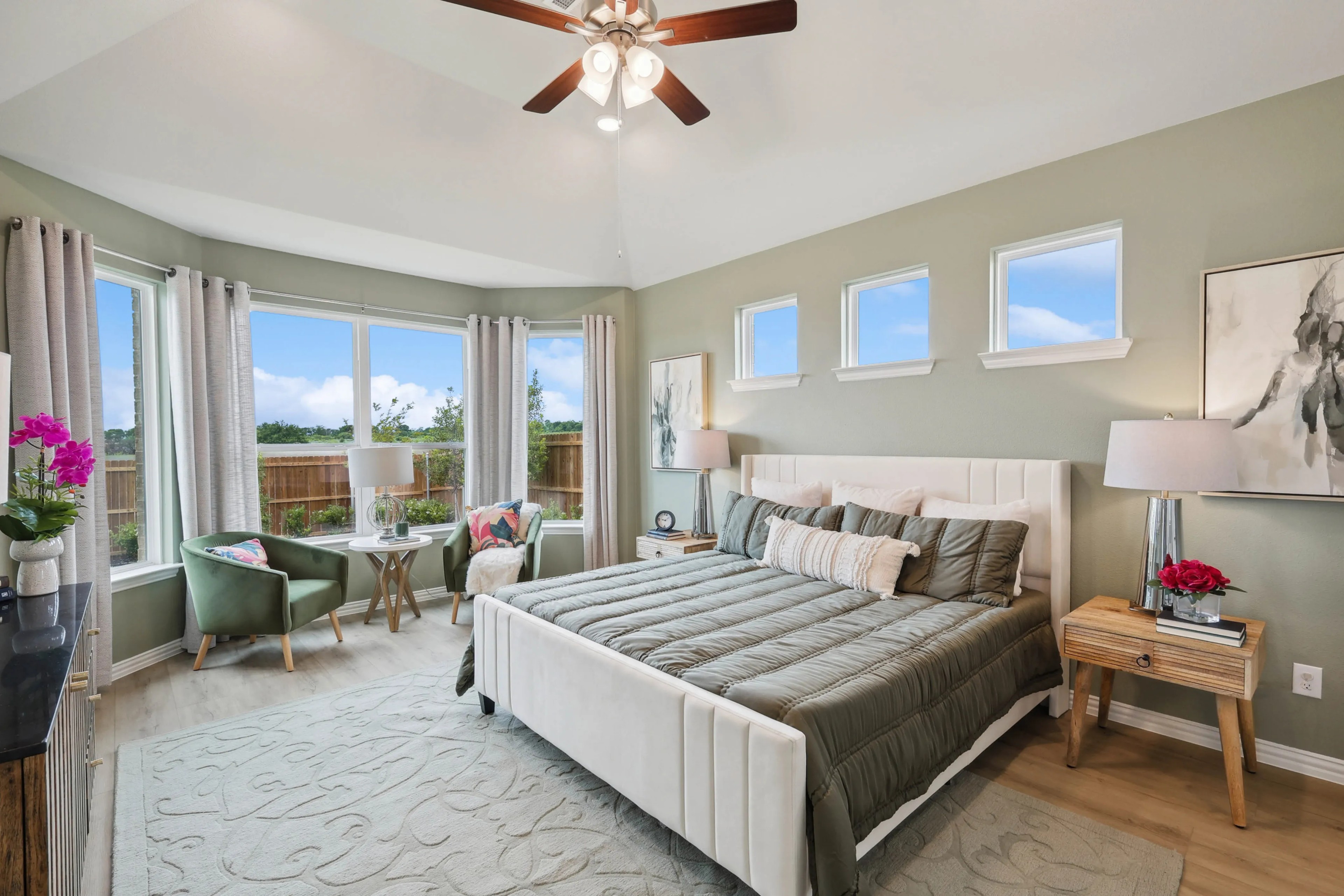 Elegant bedroom in Hulen Trails, features vaulted ceiling, large bay windows, stylish furniture, serene view.