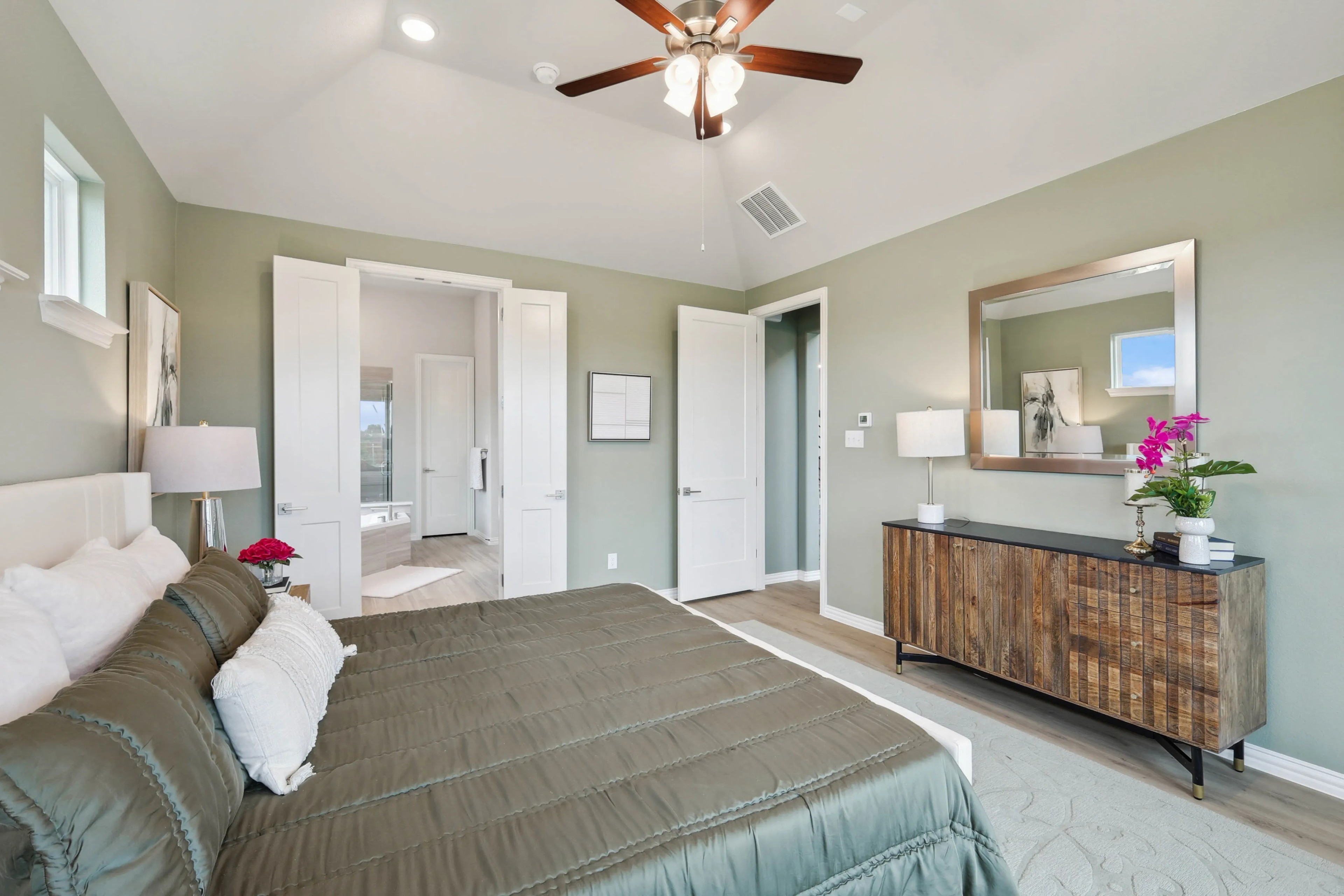 Spacious bedroom with green walls, wood accents, and en-suite bath in Hulen Trails. Features ceiling fan and modern decor.