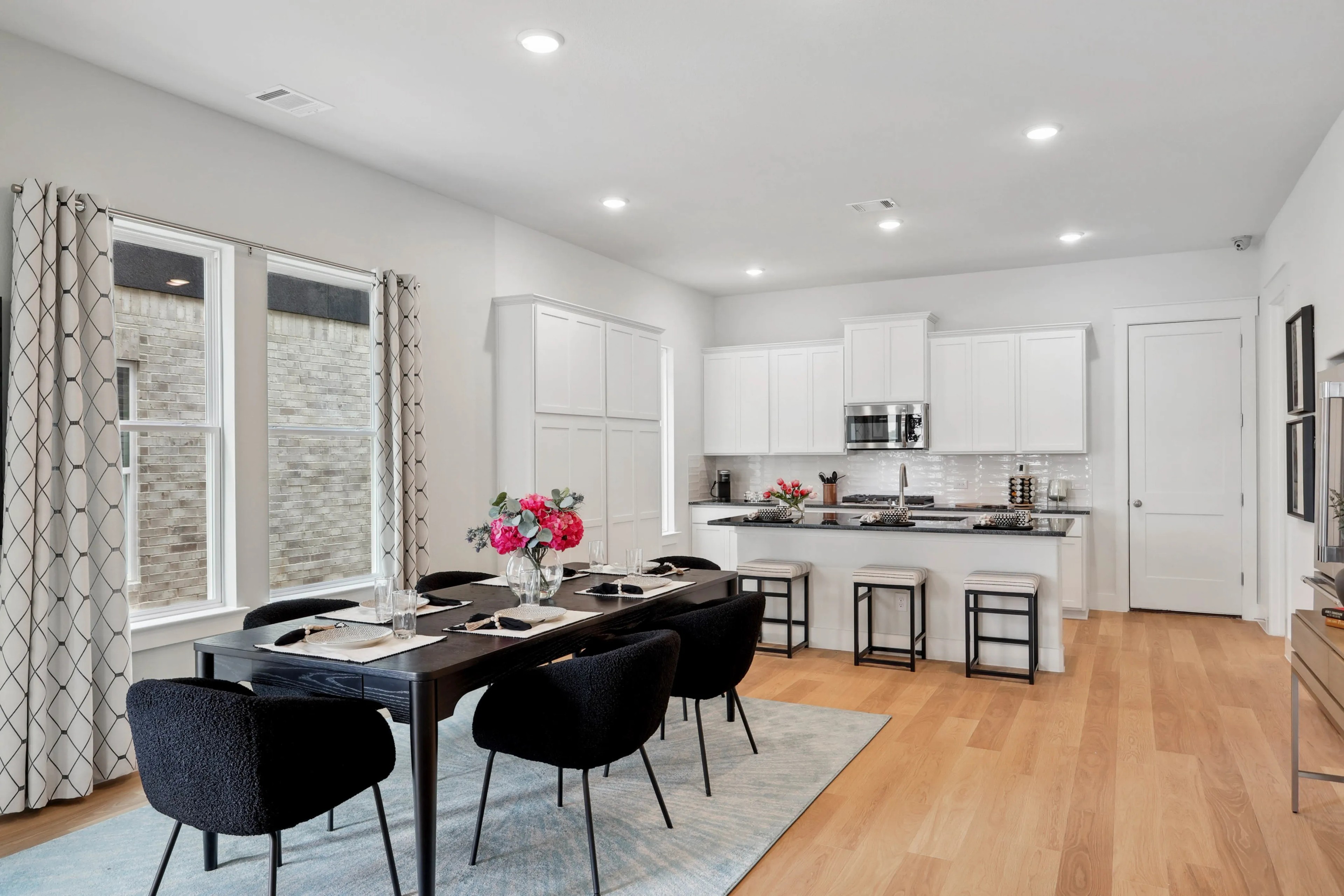 Elegant dining room and kitchen with white cabinets, hardwood floors, and floral decor in Collin Creek.
