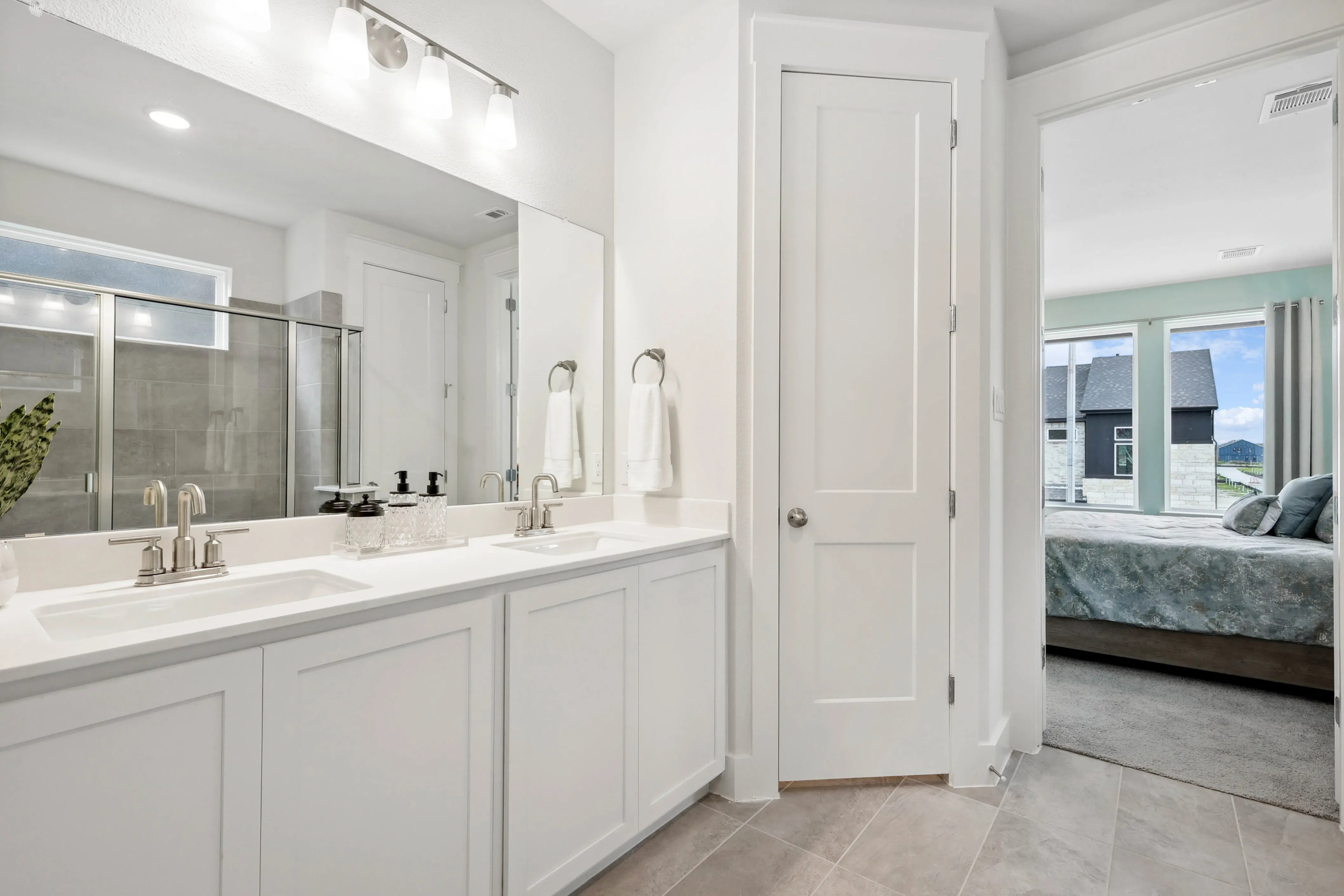 Elegant bathroom in Collin Creek with dual sinks, modern fixtures, and view into a stylish bedroom.