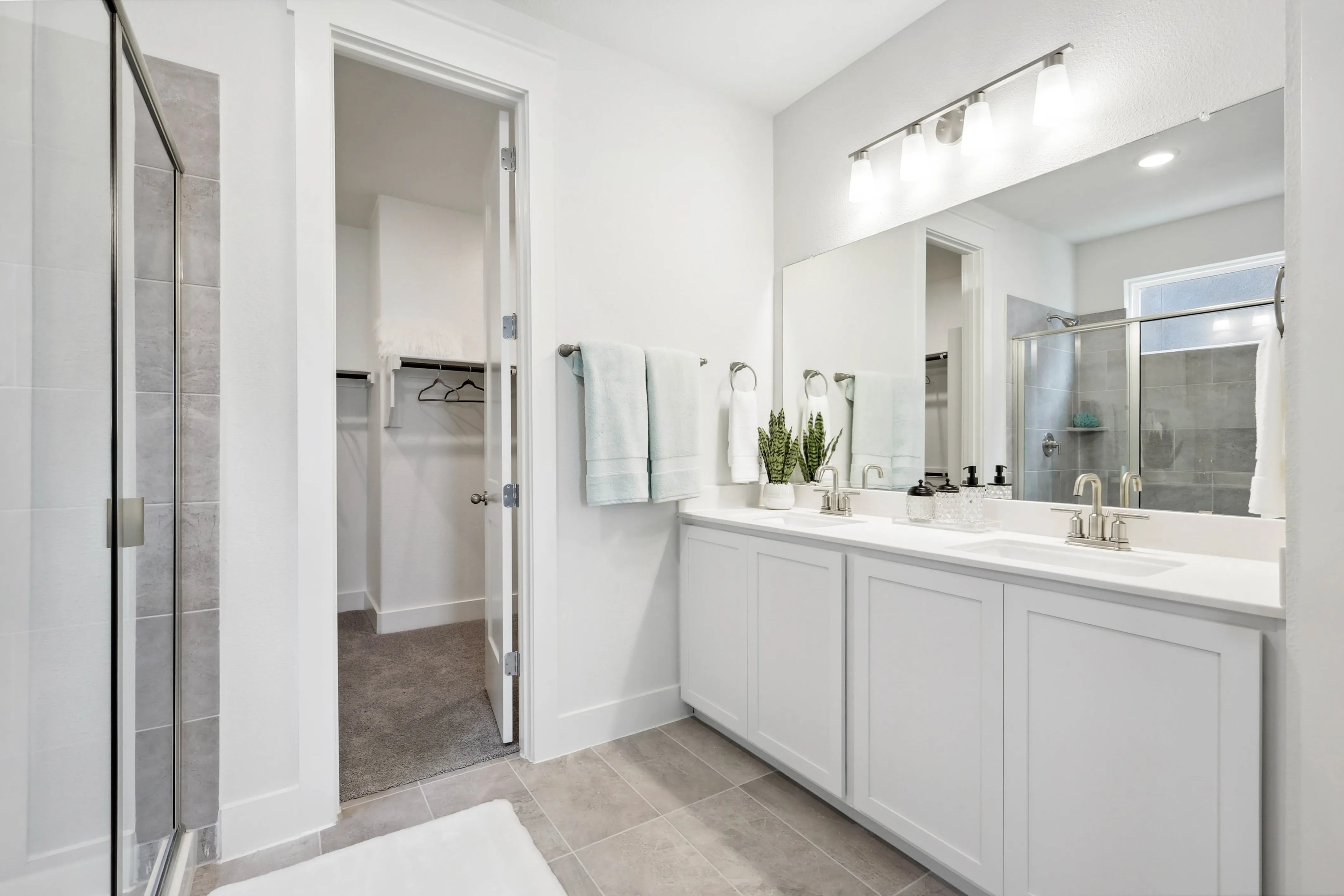 Modern bathroom with dual sinks, large mirror, and glass shower in Collin Creek. Bright, minimal design.