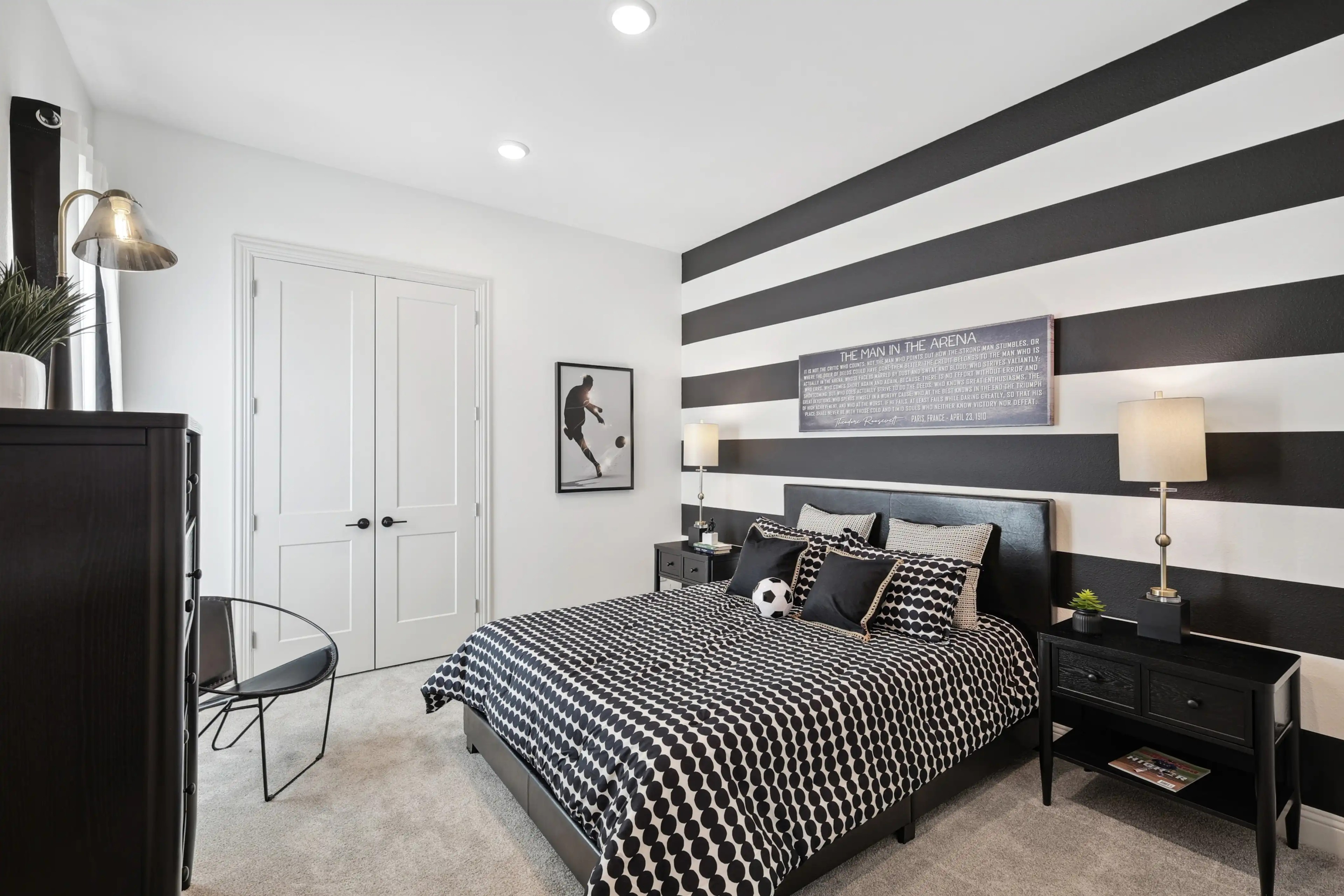 Bedroom with bold black and white striped wall, modern decor, and double doors in Westside Preserve home.