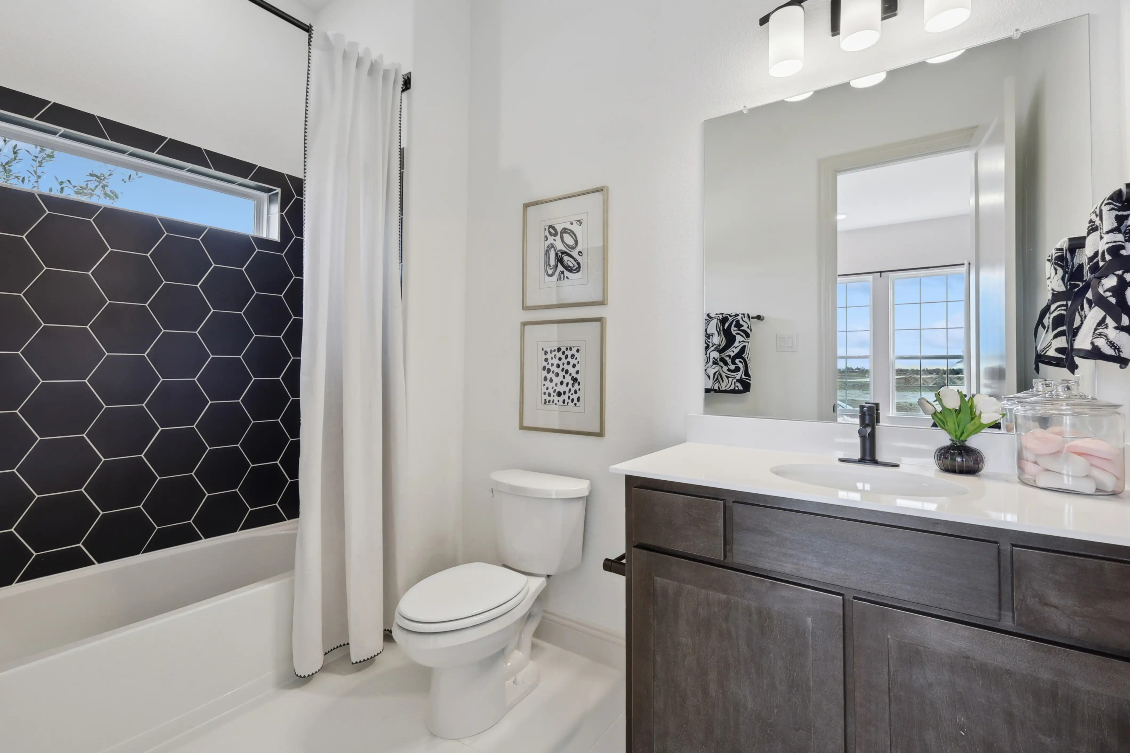 Modern bathroom with hexagonal black tile, sleek vanity, large window; Westside Preserve.