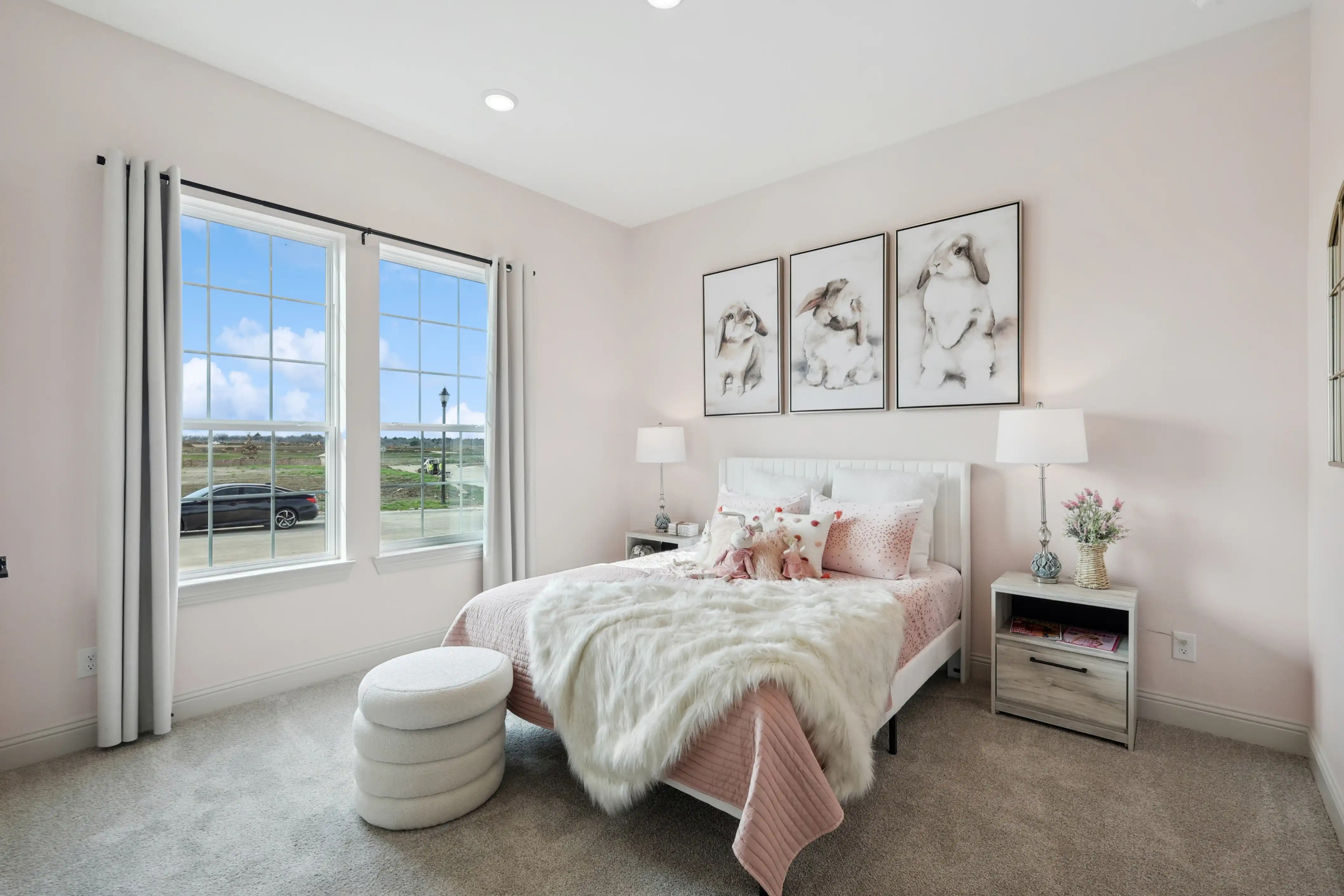 Elegant bedroom with large windows, soft pink decor, and plush bedding in Westside Preserve community.