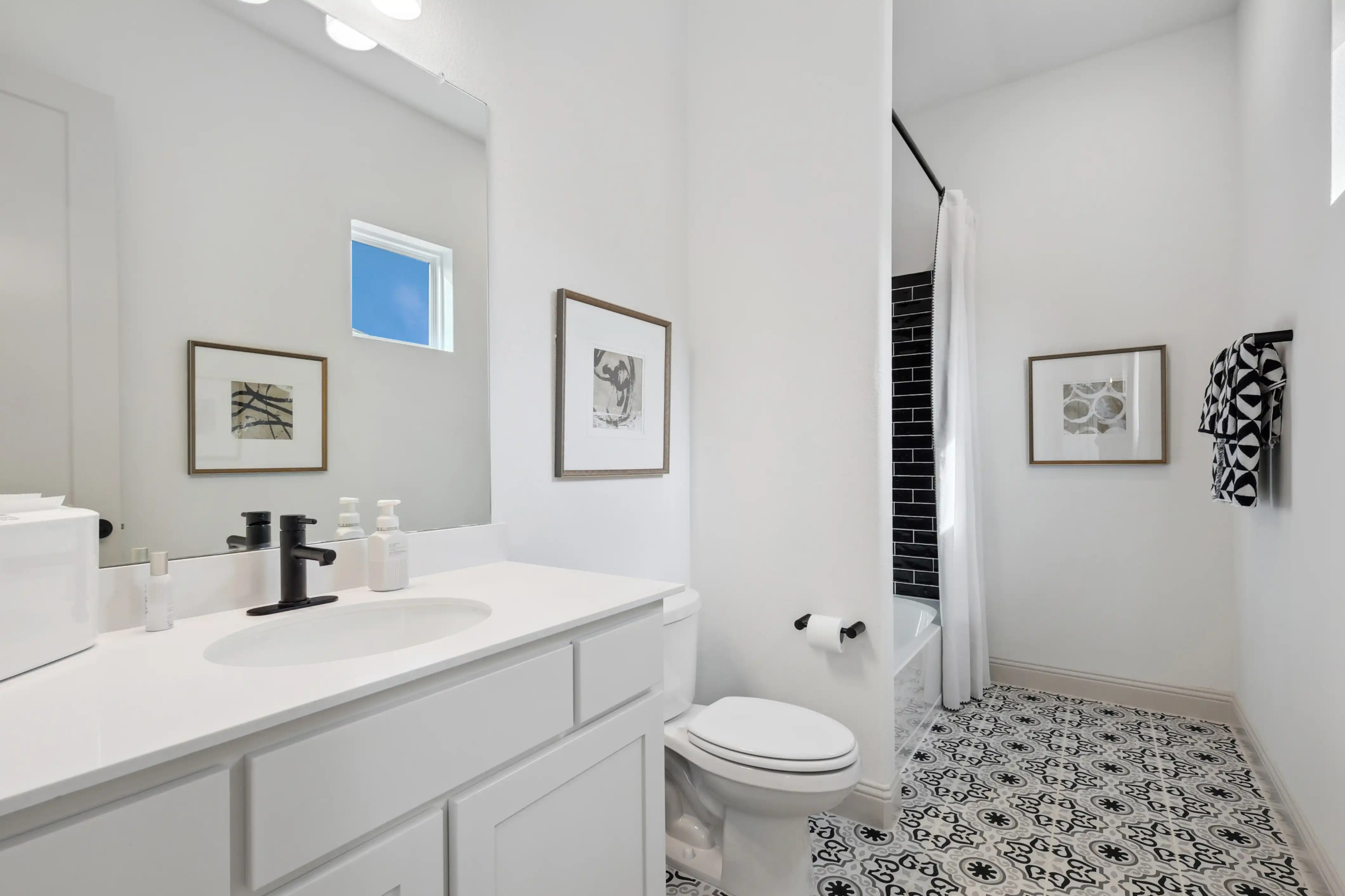 Modern bathroom with black fixtures, patterned tile floor, white walls, located in Westside Preserve community.